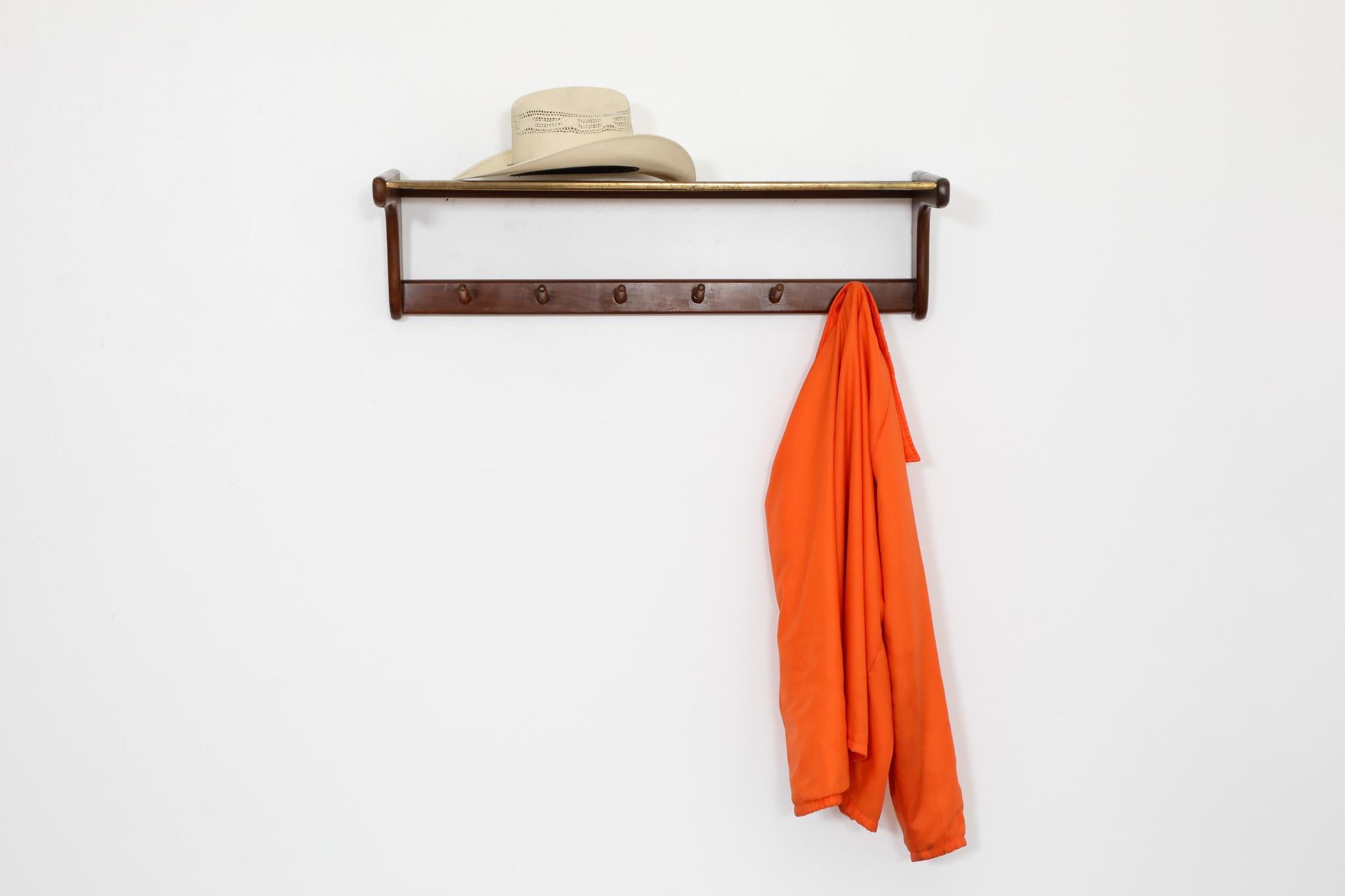 Sophisticated, Electrimeufa manufactured, Mid-Century wall mount coat rack with teak frame and hooks  and brass mesh top shelf. Attractive rustic style with soft edges and subtle patina. In original condition with wear consistent with age and use. 