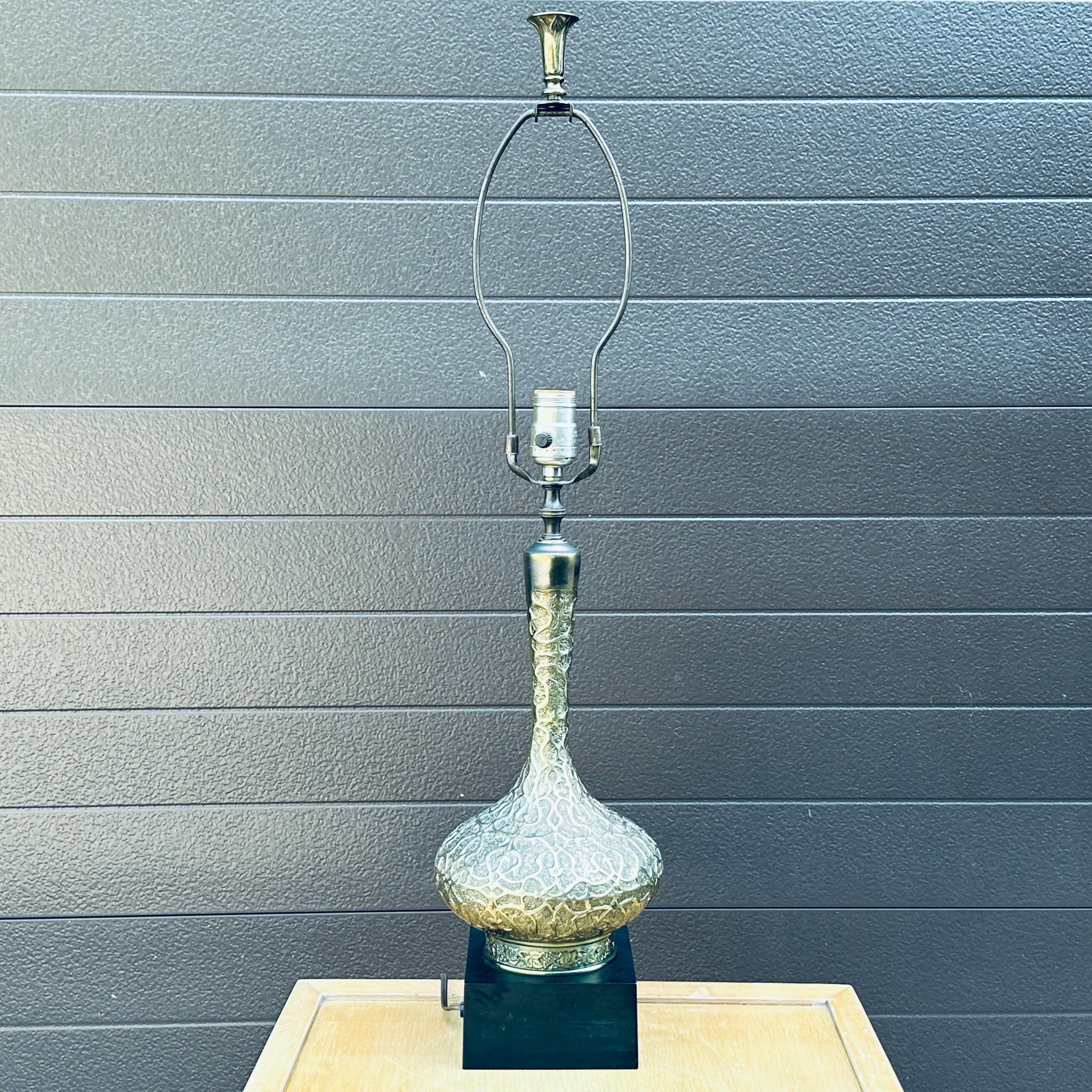Elegante lámpara de sobremesa morisca alta de latón. Intrincado diseño de estilo arabesco morisco en forma de cebolla de latón con cuello largo sobre una base negra cuadrada.
La base cuadrada mide 5