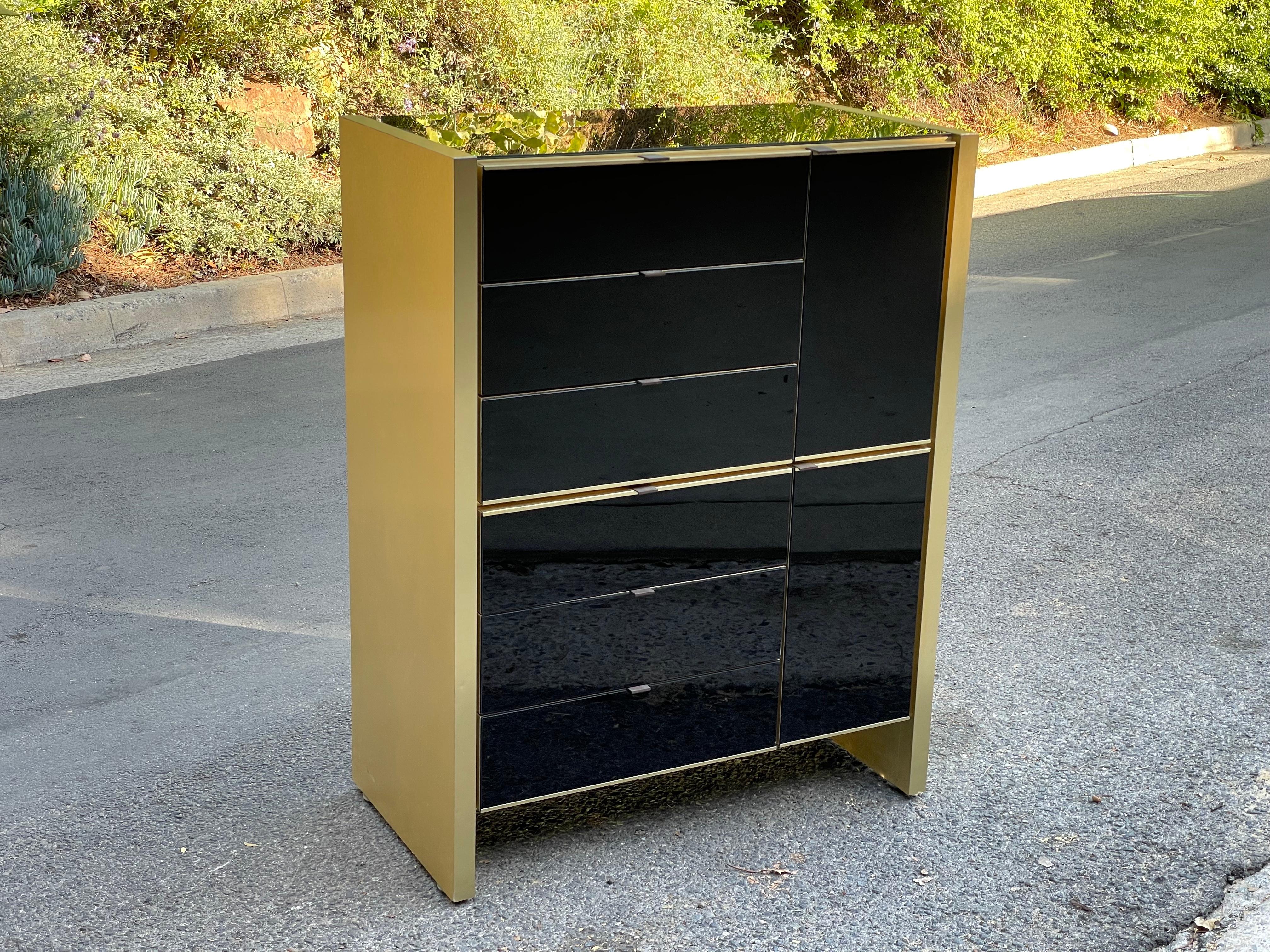 Spectacular post modern black and brass dresser / credenza / cabinet with glass faced front and top with heavy brass sides.

Steel drawer glides. Double cabinet doors. Manufactured by Ello Furniture, circa 1970s.

This black glass and brass has