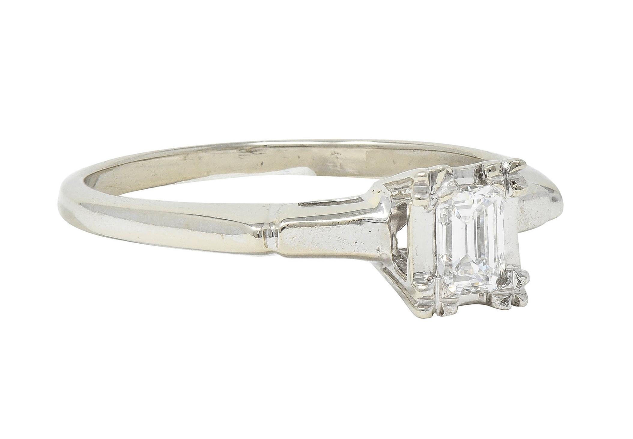 Centering an emerald cut diamond weighing approximately 0.25 carat total 
G color with VS2 clarity - flush set with tri beads in basket
With a pierced arch motif profile and cathedral shoulders
With grooved detail and high polish finish 
Stamped for