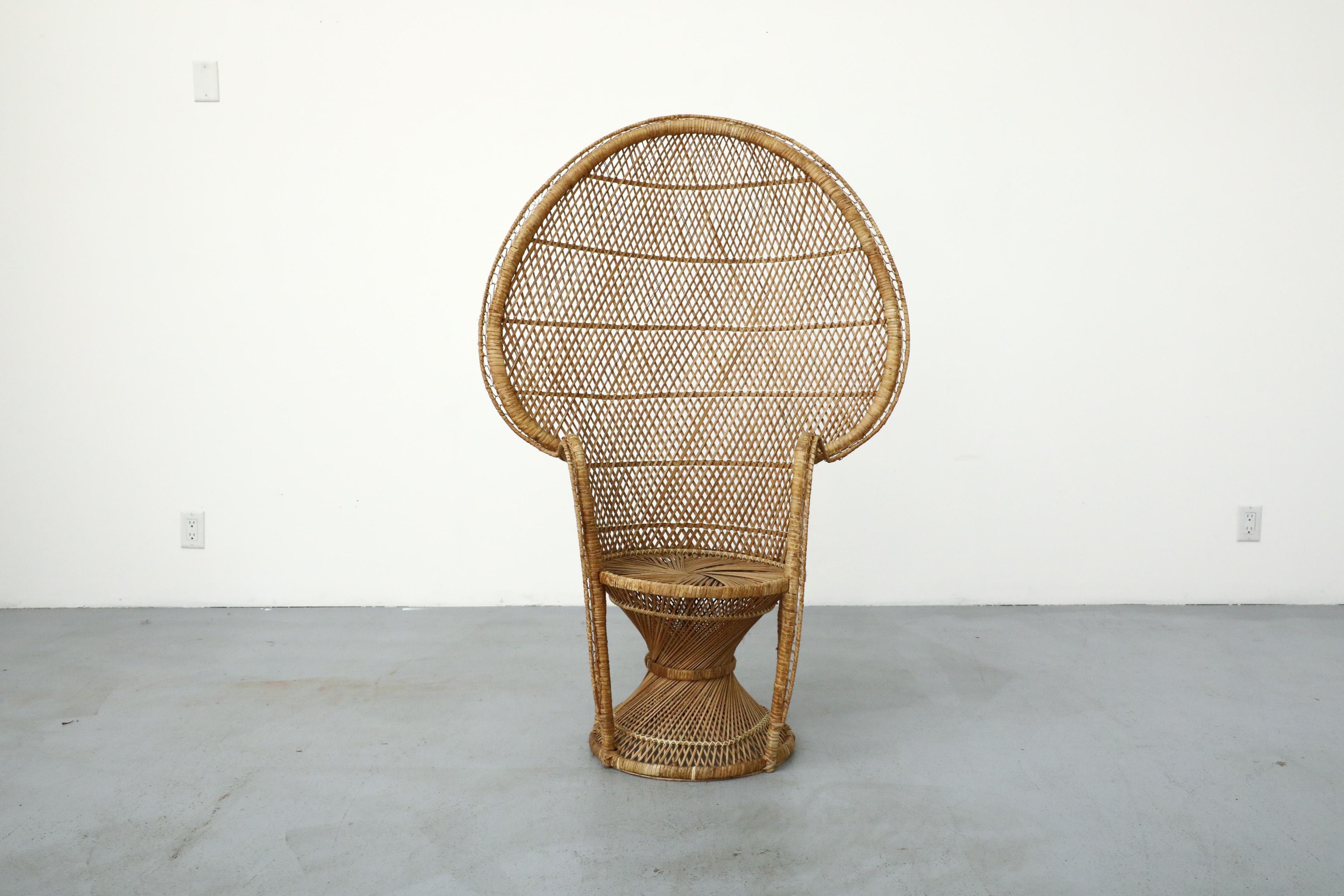 Mid-Century woven rattan peacock high back lounge chair with built-in armrests, round base and high rounded back. In original condition, with minimal wear and rattan loss. Wear is consistent with its age and use. Similar chairs available and listed