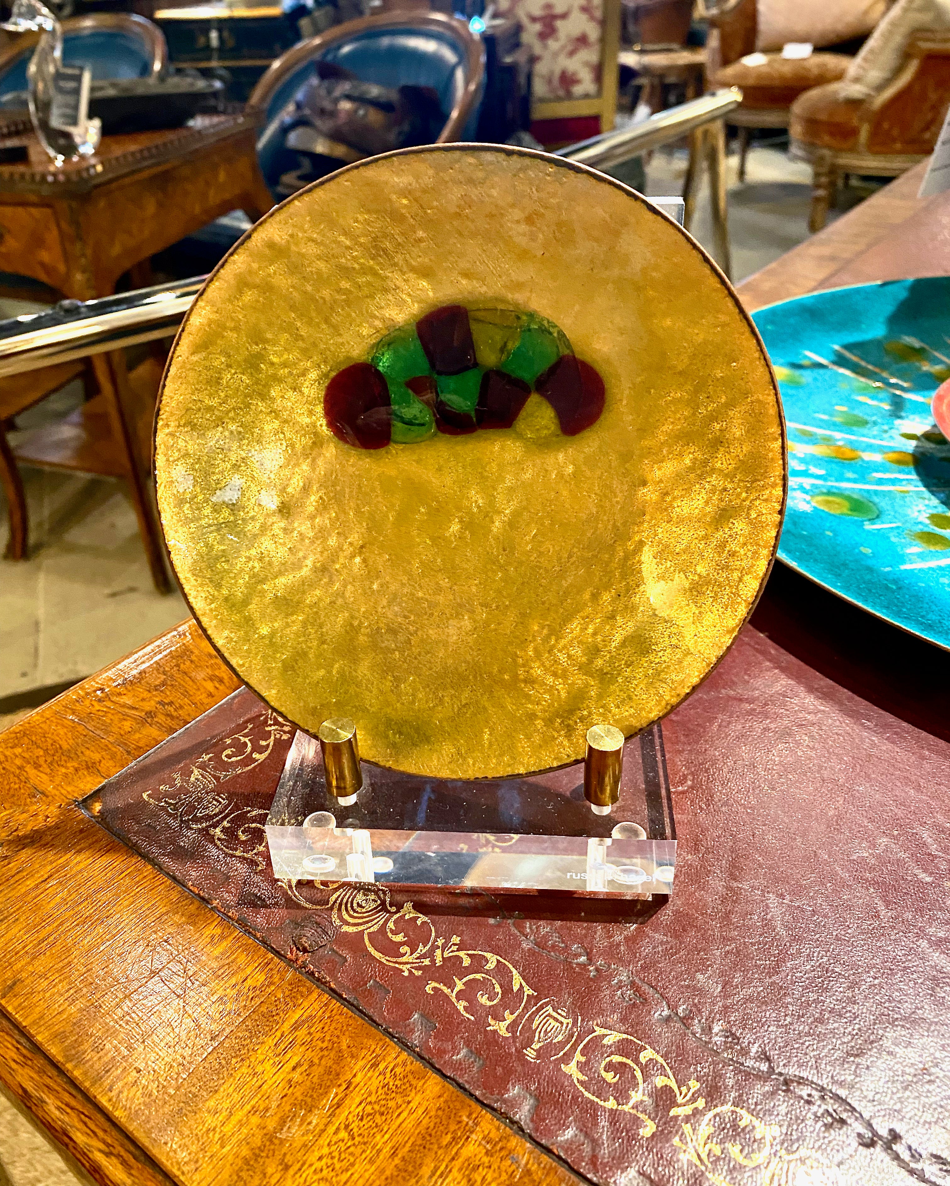 This is a charming mid-century vide-poche in enamel-on-copper. The catchall features an abstraction of multi-colored pebbles on a stunning lustrous gold enamel background. The dish can be used as a vide-poche or positioned on a stand as a table