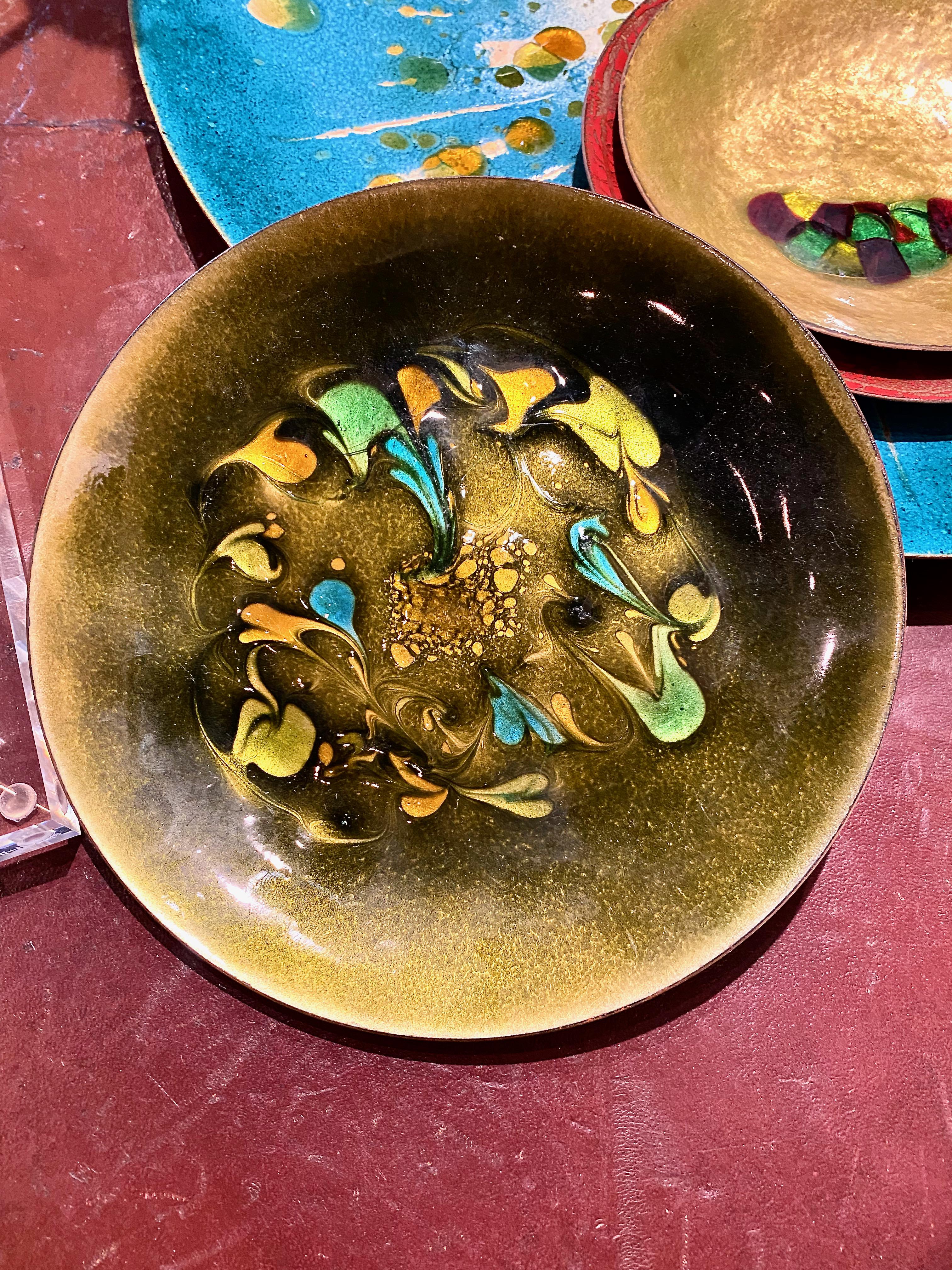 This is a good mid-century example of an enamel-on-copper vide-poche or catchall. The earth tones are reflective of the late 1960-1970s aesthetic. The dish is highlighted by frolicking abstract fish, birds and butterflies in green, turquoise, yellow