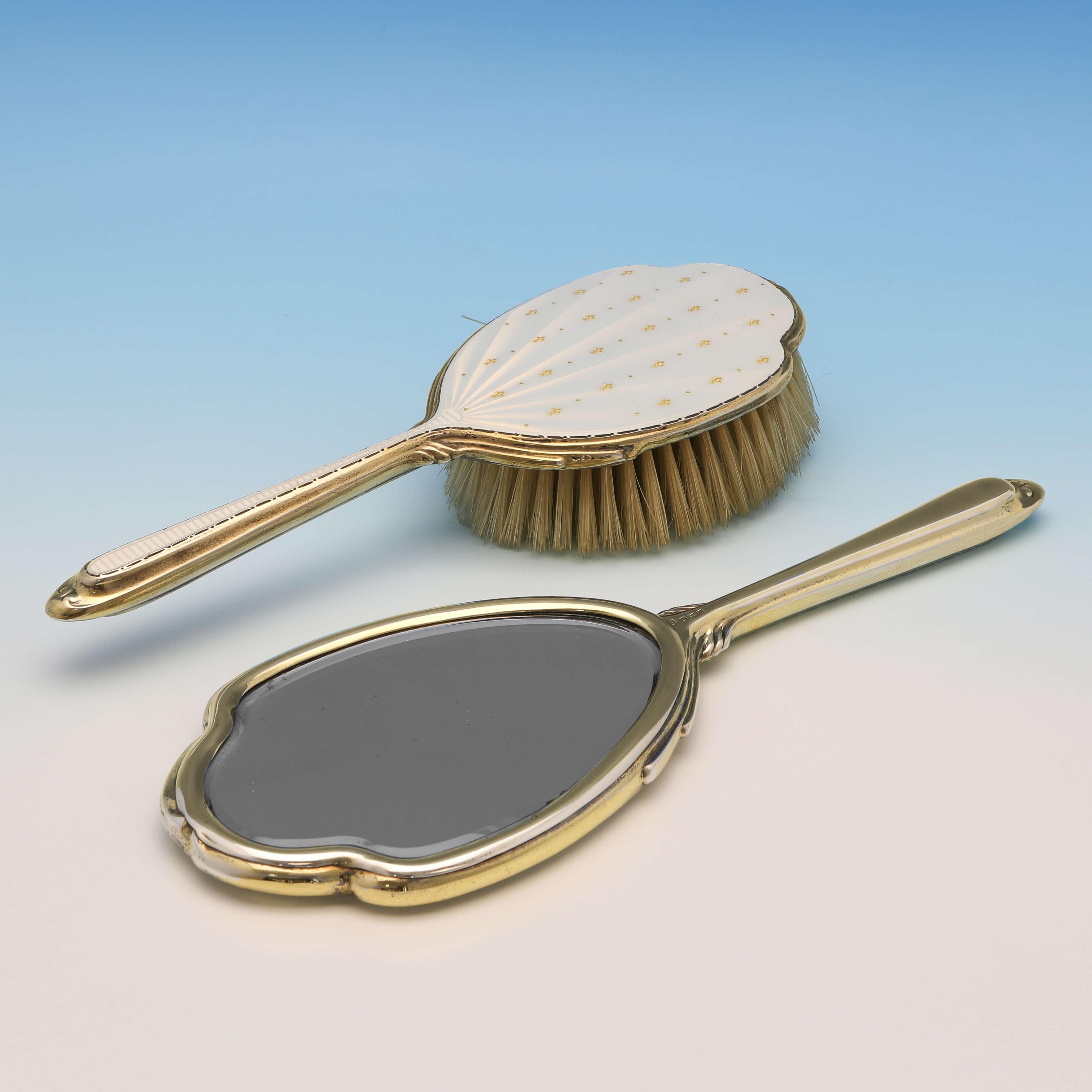 Hallmarked in Birmingham in 1961 by Albert Carter, this very attractive, sterling silver dressing table set, is gilt, and features enamelled decoration to the backs of each piece. The hand mirror measures 11.25