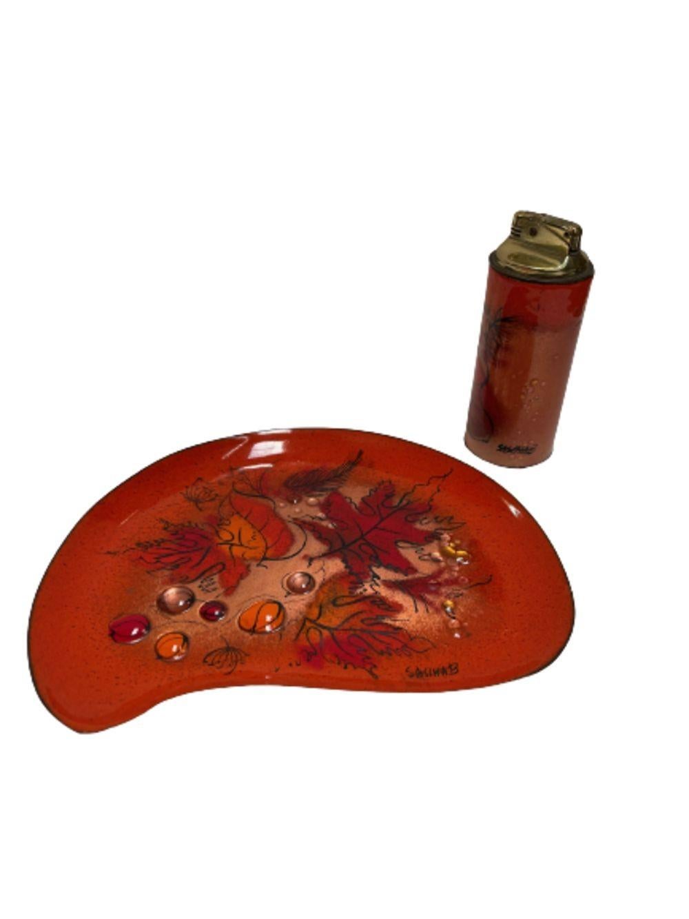 Original matching enameled brass cloisonne Ashtray and Lighter featuring an Autumn, Fall scene of changing leaves by Sascha Brastoff. The ashtray features a biomorphic shape hand painted fall maple leaves with the matching gas lighter featuring the