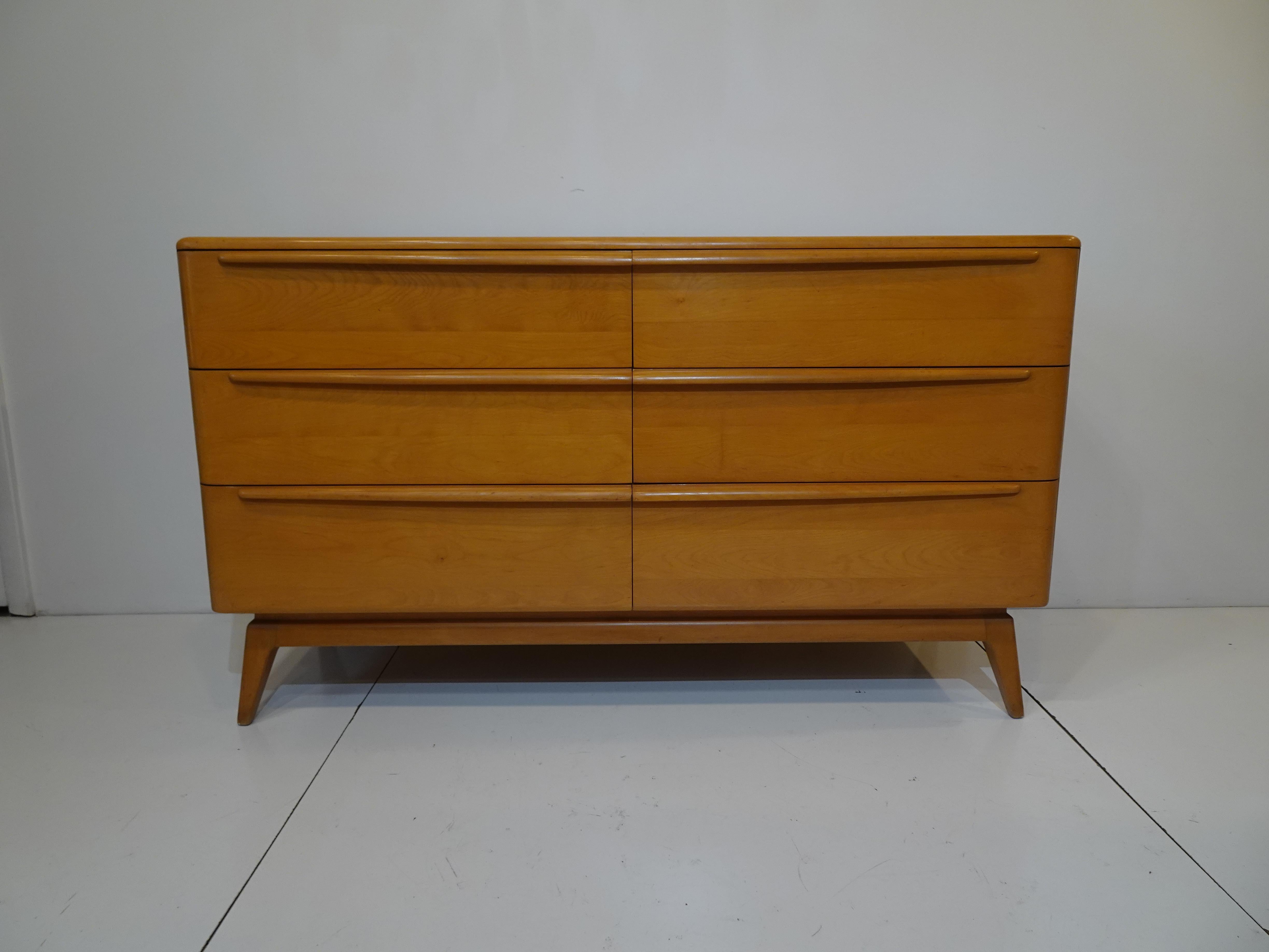 A well crafted solid wood mid-century dresser chest with six drawers having long sculptural pulls sitting on tapered legs and a lifted base giving the piece a light and airy feel. From the Encore Collection the front has rounded top corners and