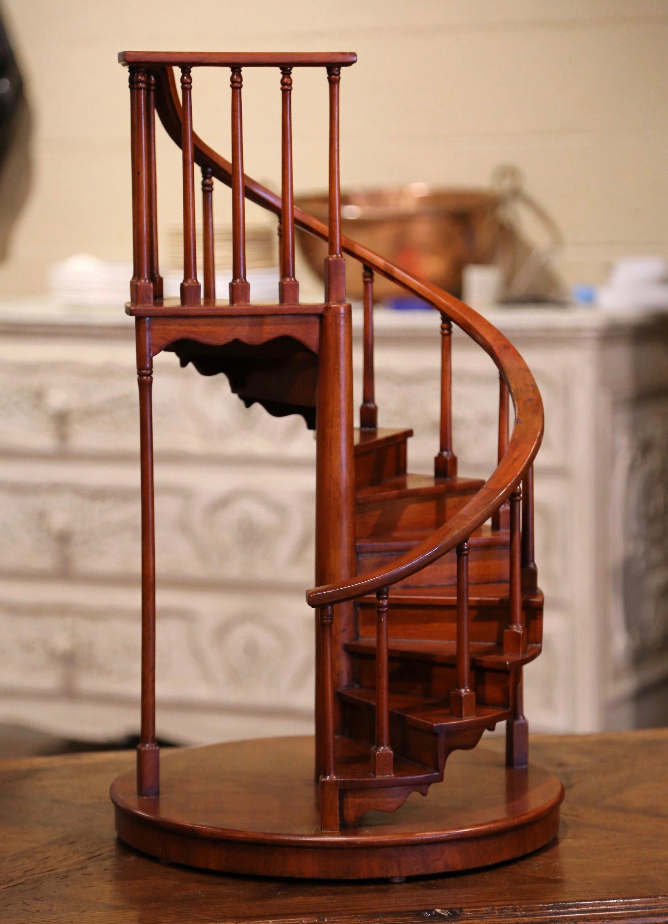 Decorate an office or study with this elegant petite architect staircase; hand carved in England circa 1950 and made of mahogany, the stair model rests on a circular base over a central stem, and features ten spiraling stairs decorated with