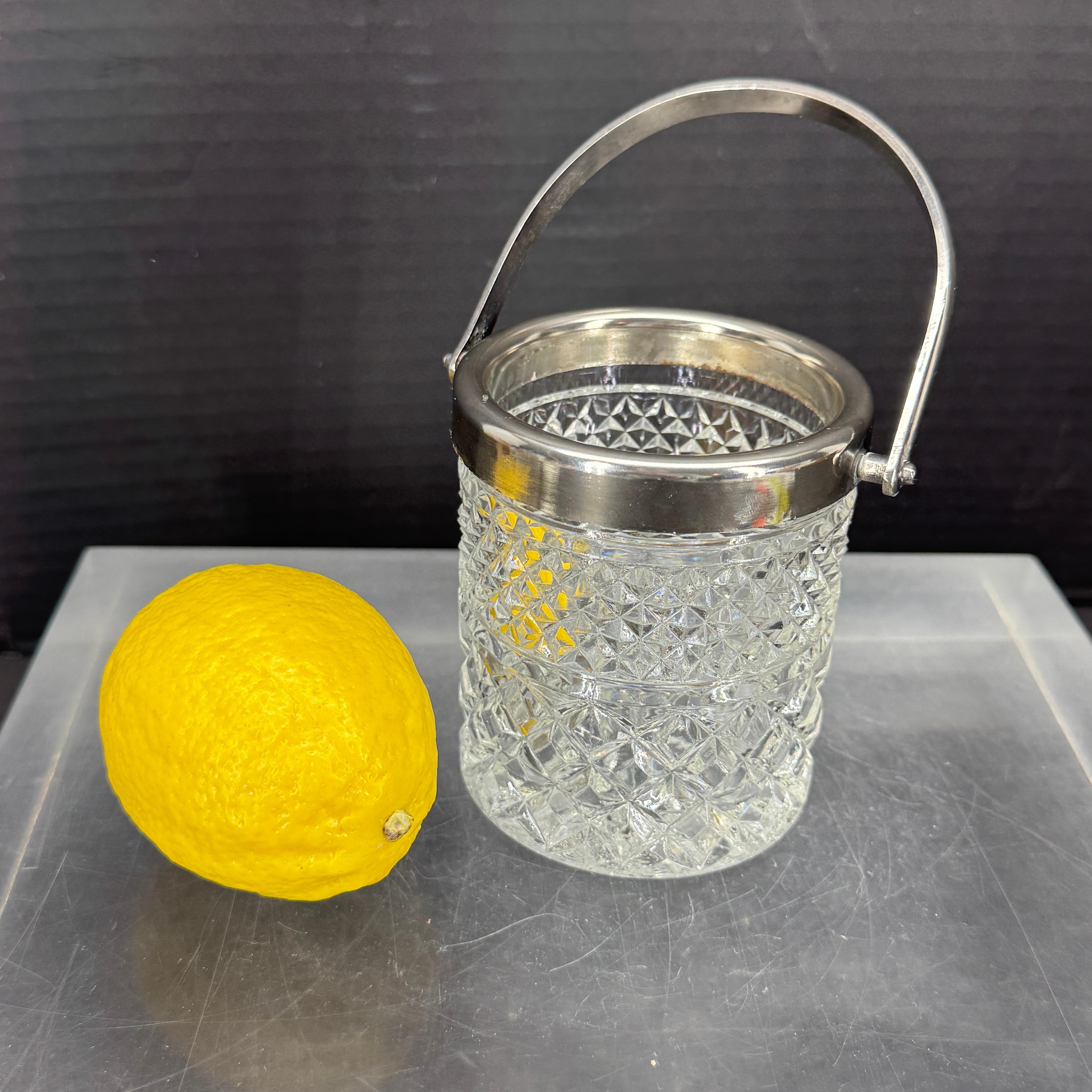 Pequeña cubitera de cristal moderna de mediados de siglo. Esta cubitera es tan bonita como funcional. El chapado está alrededor de la parte superior del cubo, así como el asa. Fantástica pieza clásica para añadir a tu bar moderno.