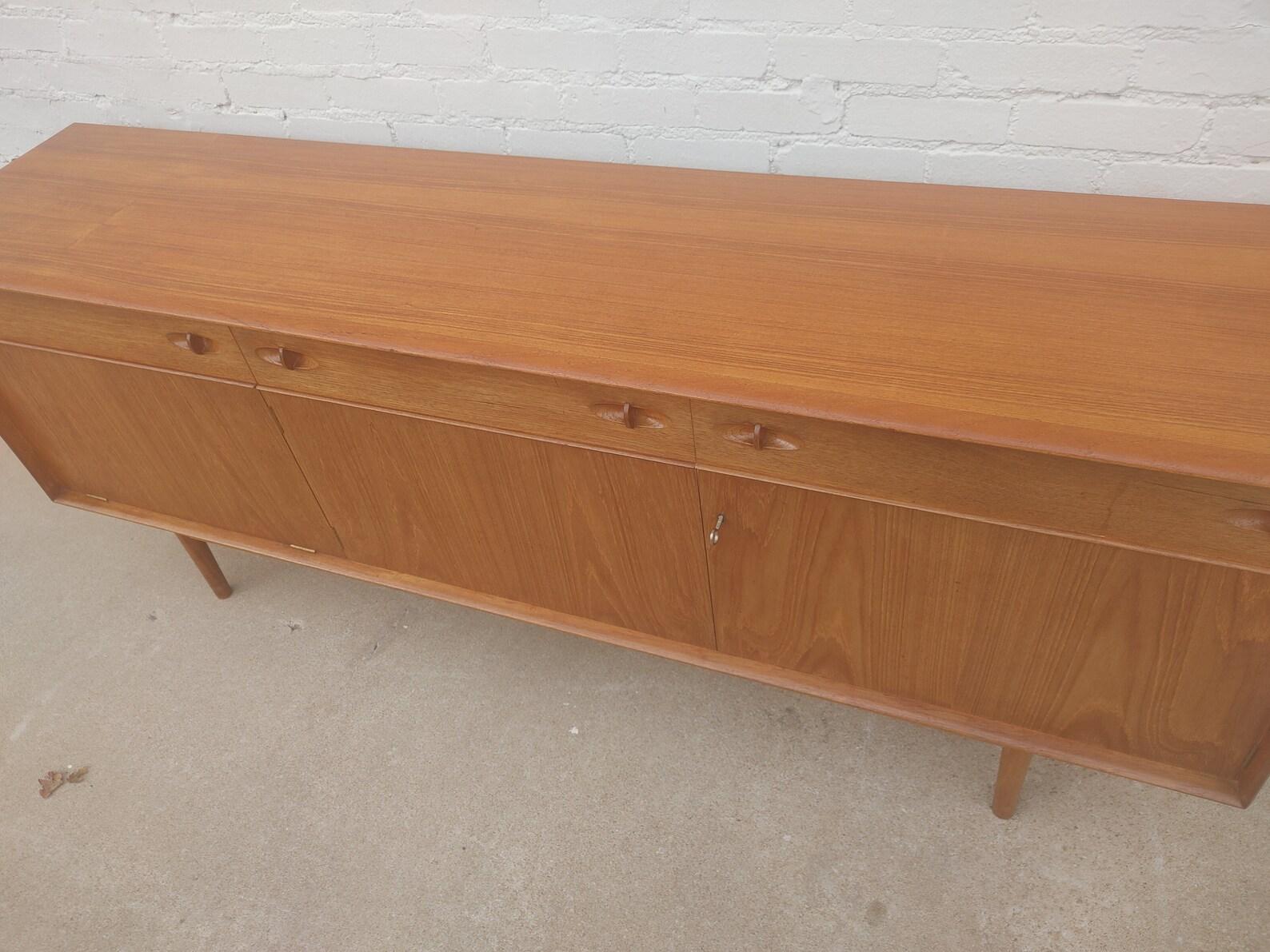 Mid Century English Modern Teak Sideboard

Above average vintage condition and structurally sound. Has some expected slight finish wear and scratching. Top has been refinished and does not have original factory finish. Back is finished. Outdoor