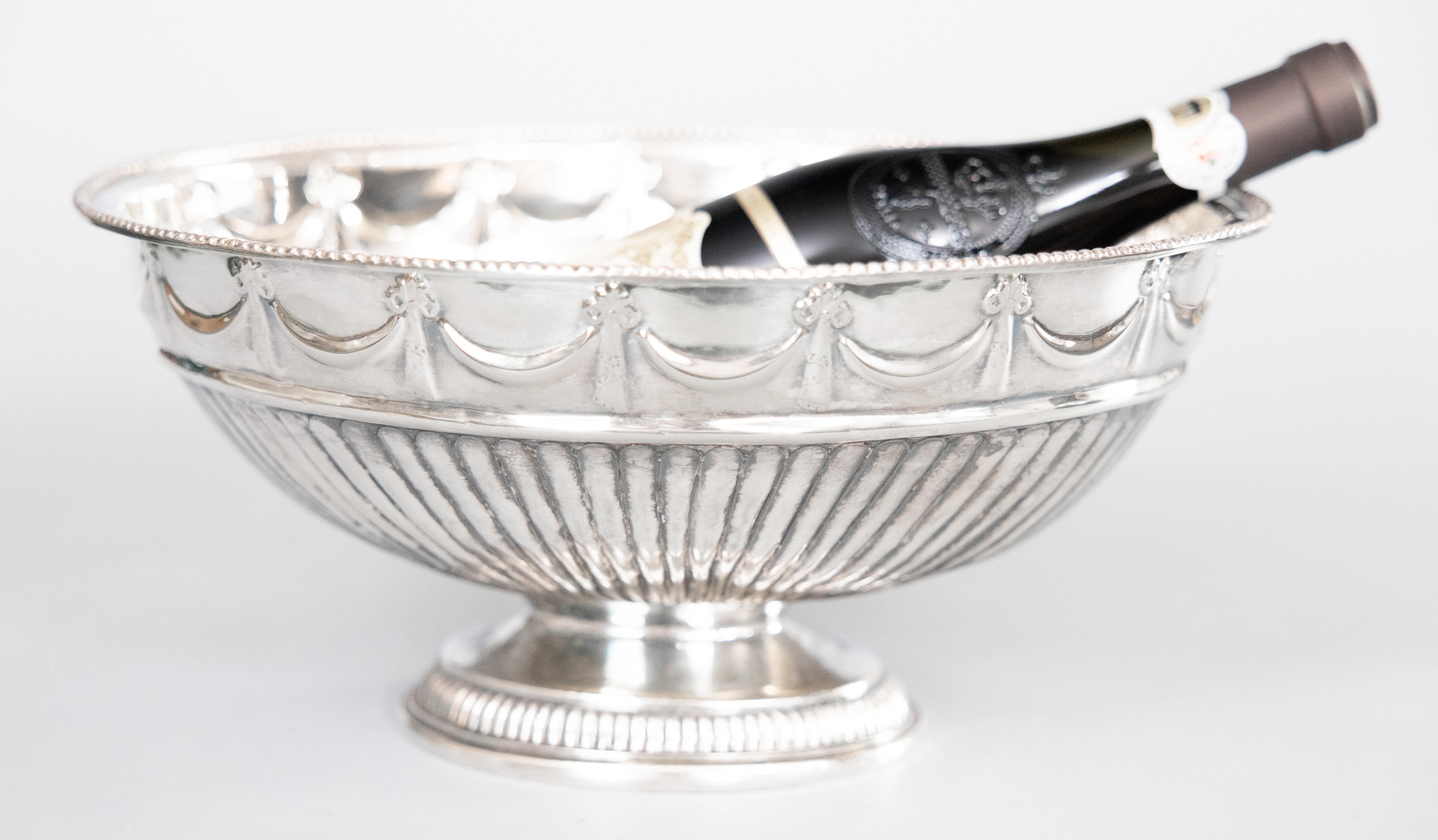 A stunning large Mid-Century English silver plate oval pedestal bowl, punch bowl, wine cooler, or champagne ice bucket. No maker's mark. This gorgeous bowl is decorated with draped bows and ribbons, gadrooned details, and a beaded rim in a lovely