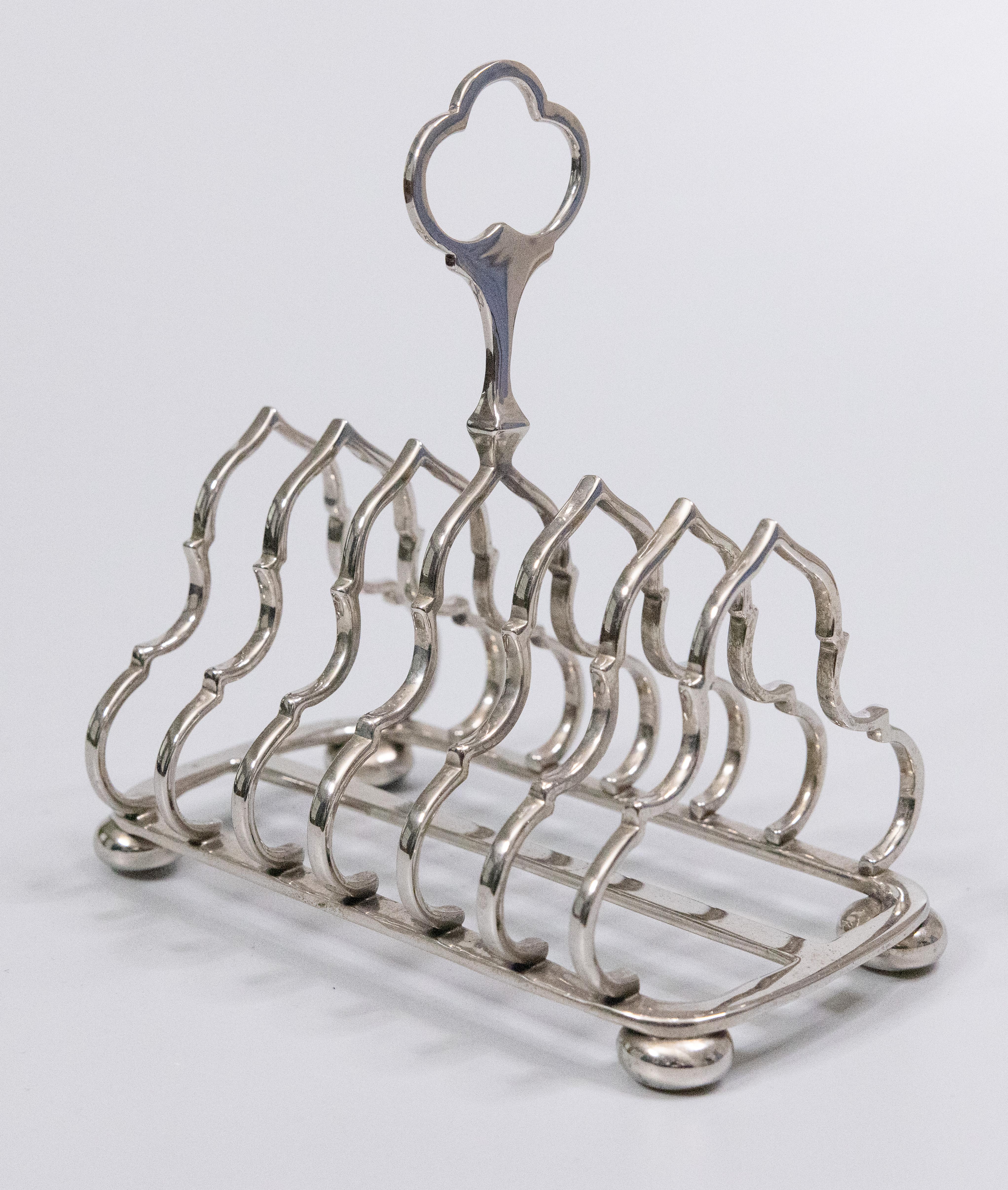 A superb vintage English silverplated six slice toast rack. This Fine quality silver toast rack is well made and heavy with a lovely Gothic shape, decorative finial, and charming bun feet. It would be wonderful for serving toast or could also be