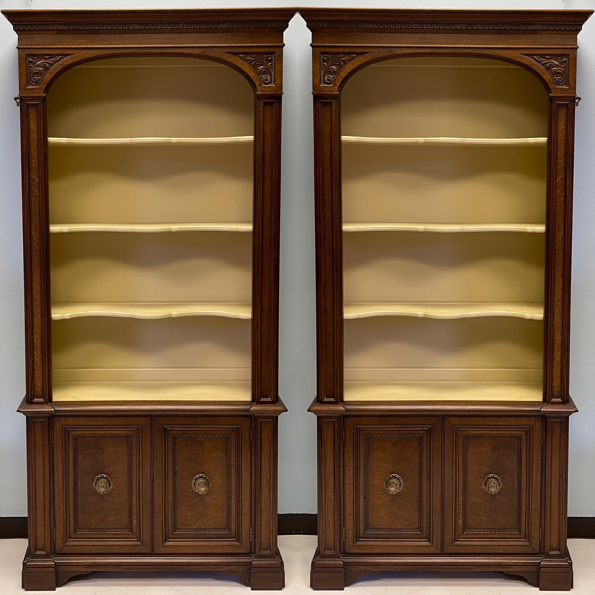 These wonderful bookccases are carved fruitwood with burled doors. The top portion has serpentine styling, and the paint could be interpreted as a soft yellow or warm ivory. They are unmarked and in very good condition. It is 12 inches between the