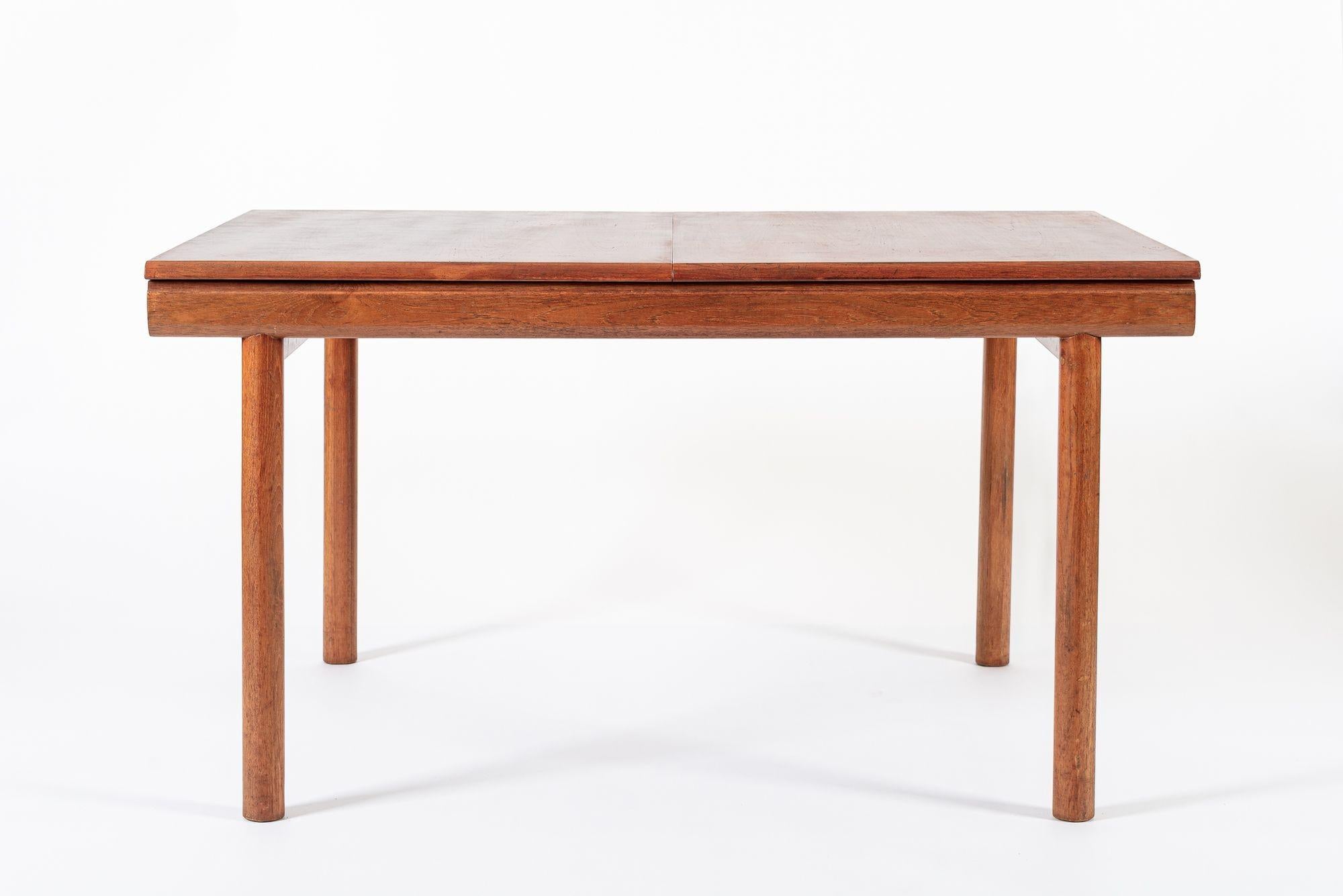 This unique vintage mid century English modern extendable teak dining table by White and Newton was made in England circa 1960. This beautiful table has clean, minimalist lines and is well constructed from solid wood and teak veneer. The unique