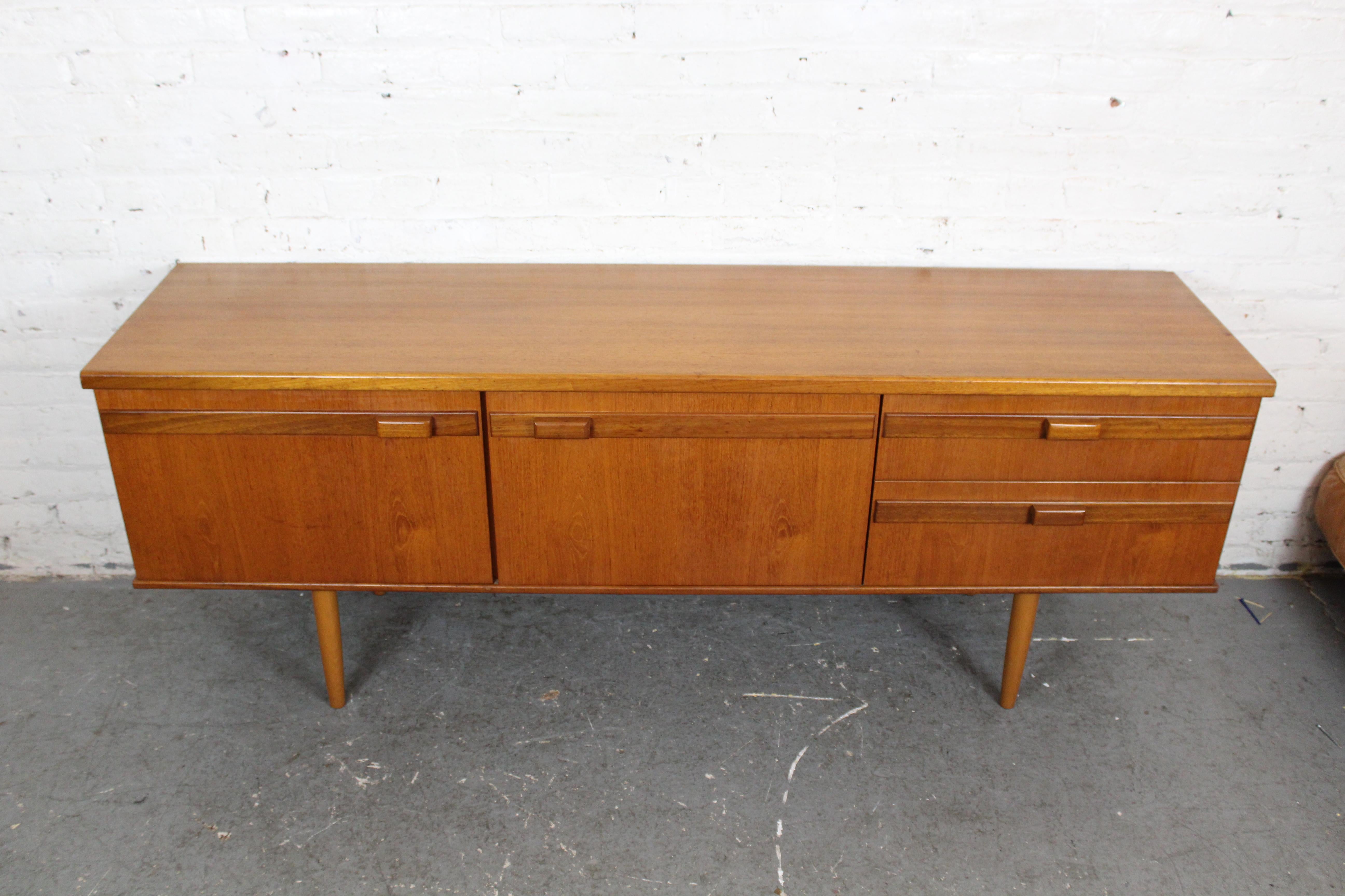 Holen Sie sich Vintage-Möbel nach Hause, die einem König (oder einer Königin) würdig sind, mit diesem atemberaubenden englischen Sideboard aus Teakholz von Portwood Furniture aus Stockport, England! Mit einem großen zweitürigen Schrank und zwei