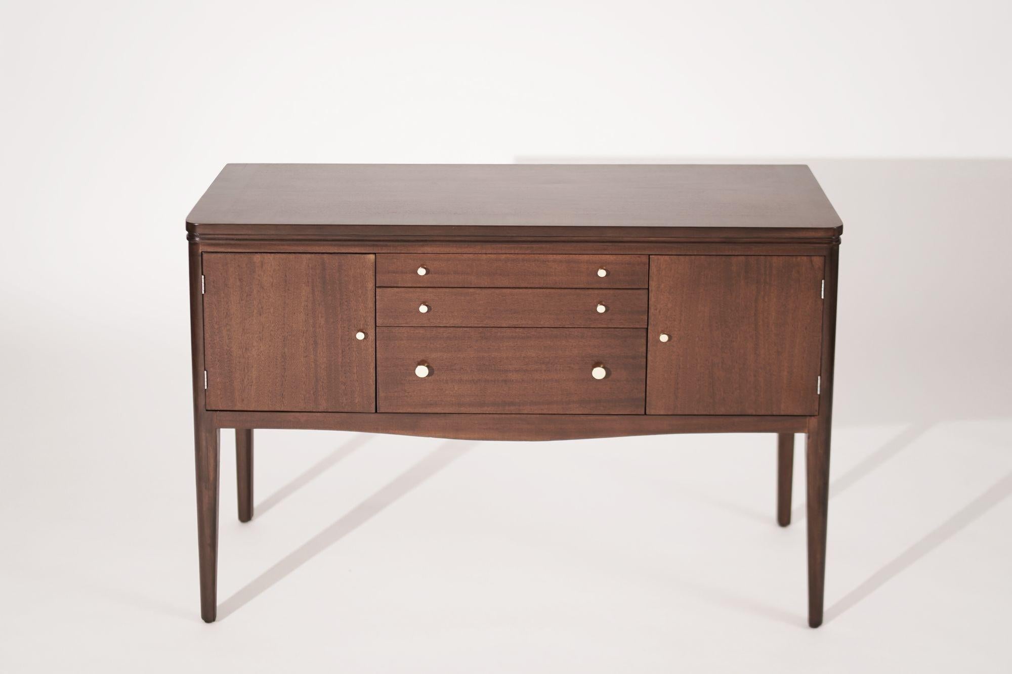 An outstanding console table executed in mahogany with brass hardware, three drawers, and side doors provide plenty of storage space. Completely restored. 
 
Other designers from this period include Paul McCobb, Paul Frankl, Jens Risom, and T.H.