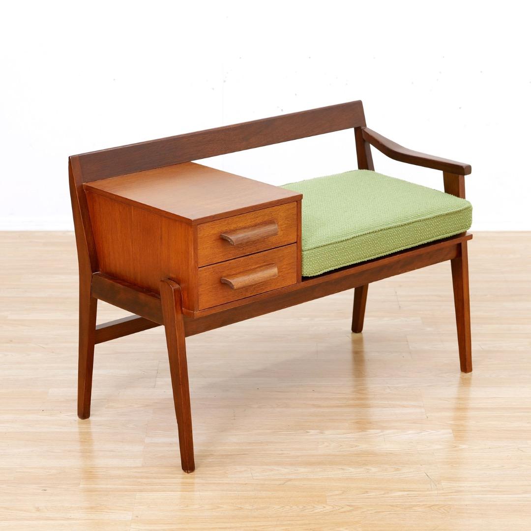 Este banco de entrada de mediados de siglo tiene un diseño maravilloso y una estética escandinava. Fabricado en Inglaterra en los años sesenta, con dos cajones de almacenaje y asiento recién tapizado, es perfecto para la entrada o el salón.