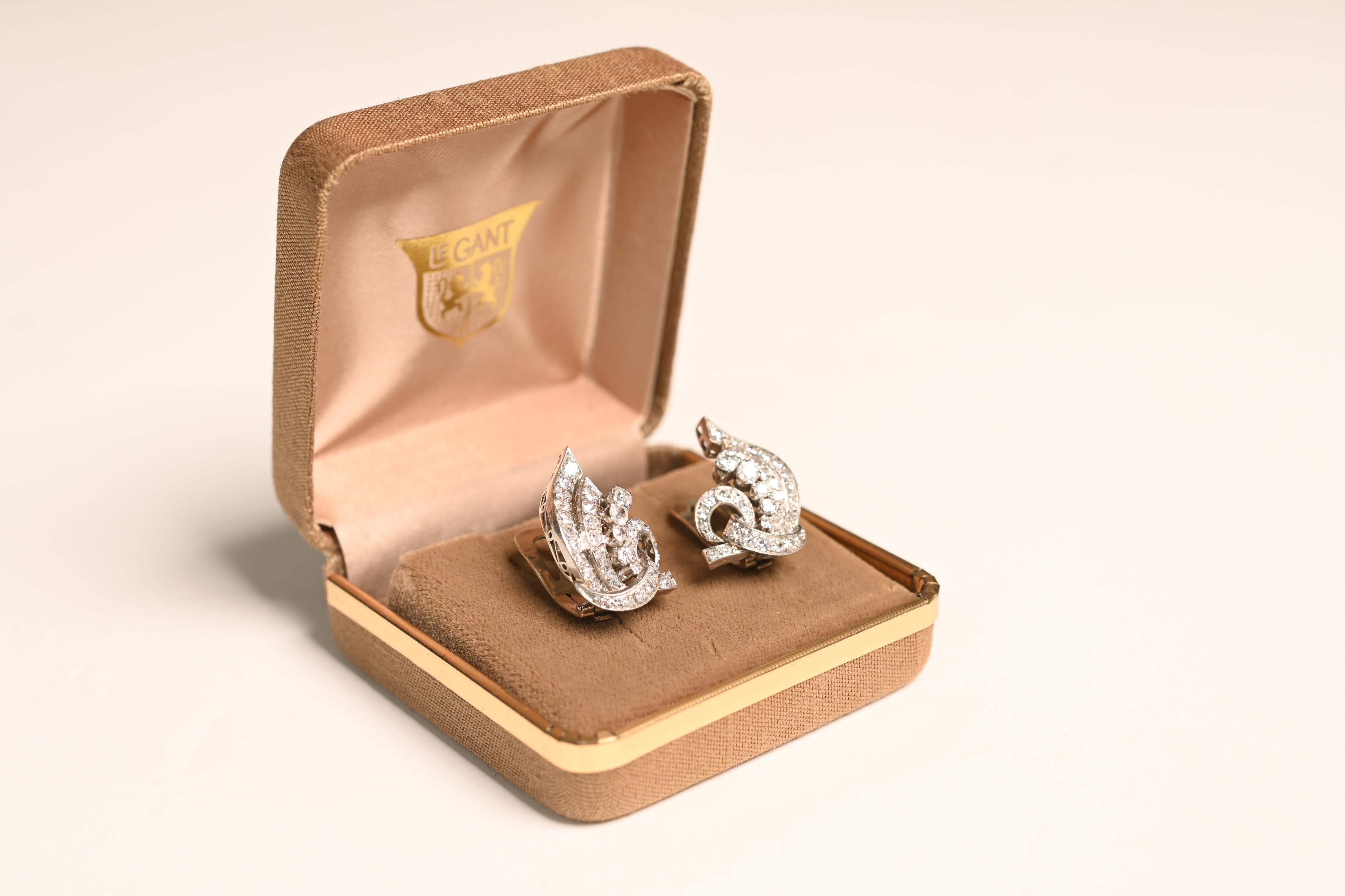 Une paire vraiment exquise de boucles d'oreilles vintage en diamant, méticuleusement fabriquées à la main en platine au cours de l'ère du milieu du siècle, vers 1950. Ces élégantes boucles d'oreilles présentent un motif de volutes sophistiqué, avec