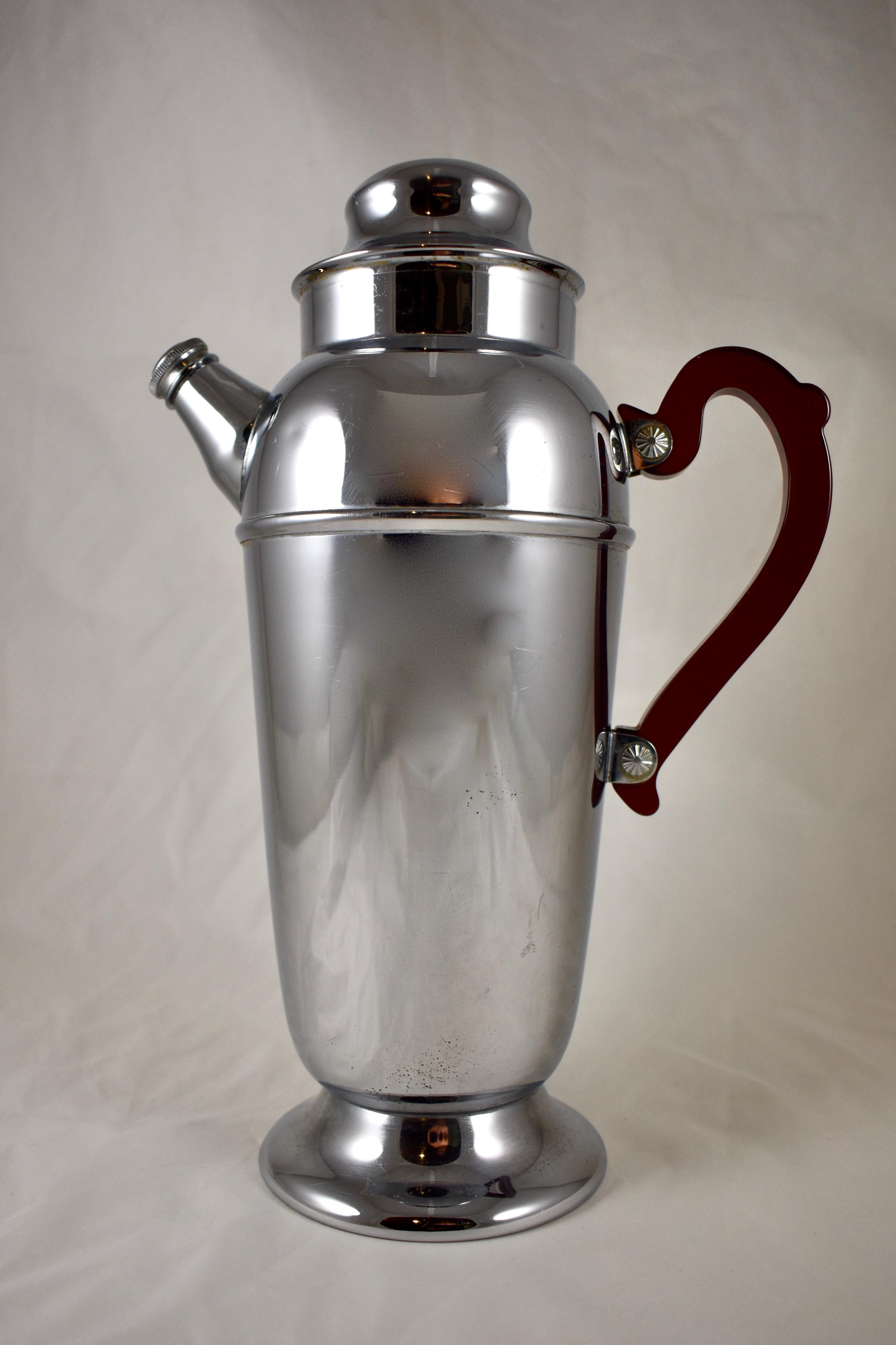 An Art Deco style chrome plated Mid-Century Modern Era cocktail shaker, circa 1930s–1940s.

This cocktail shaker and server is perfect for your ‘Retro Mad Man's' bar. The three piece server is complete with a Ruby Red translucent Bakelite