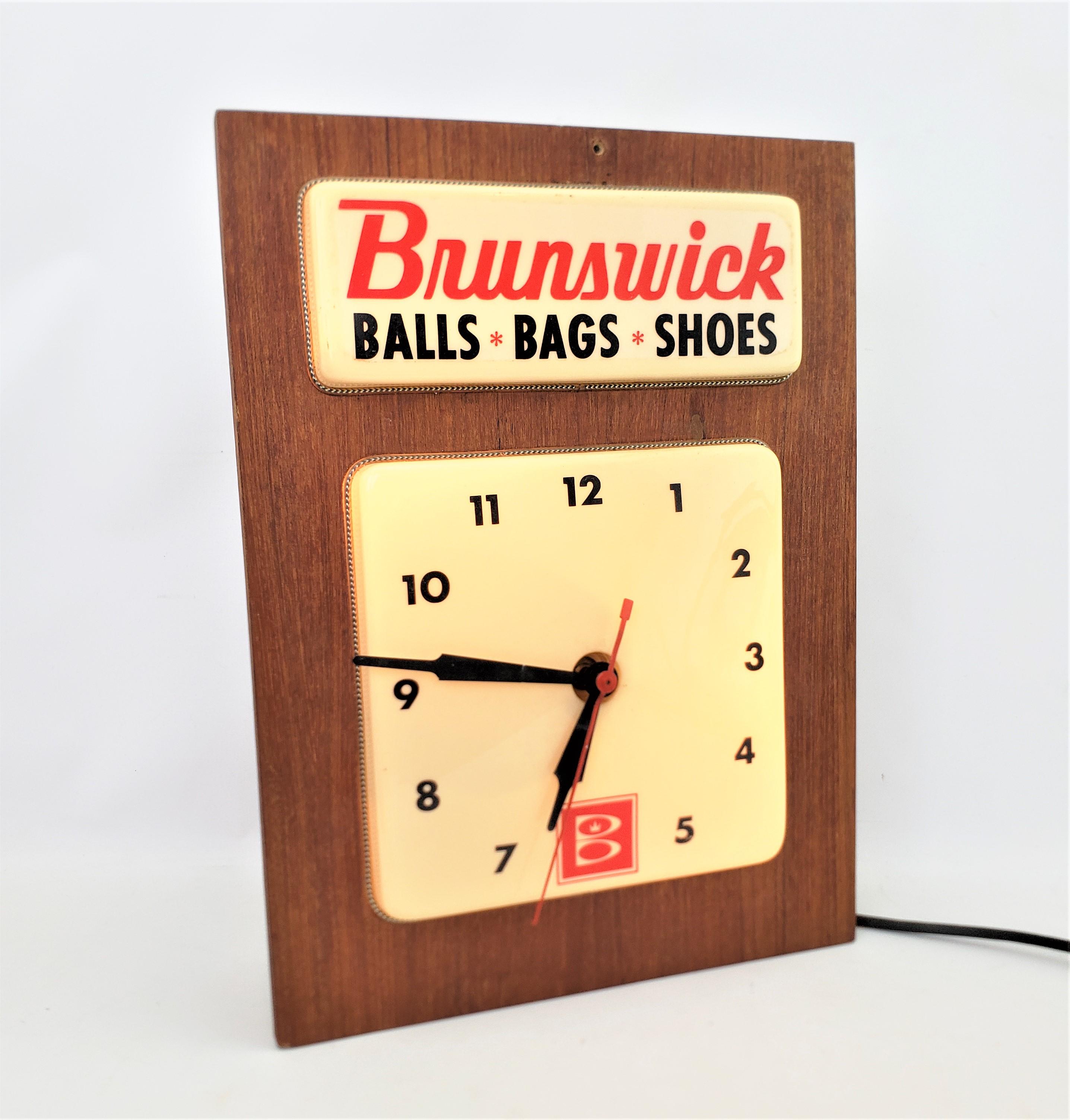 This wall clock was made by the McCallum Advertising Company of Canada in approximately 1965 and in the period Mid-Century Modern style. The lighted clock or sign advertising the bowling products made by the well known Brunswick sporting good