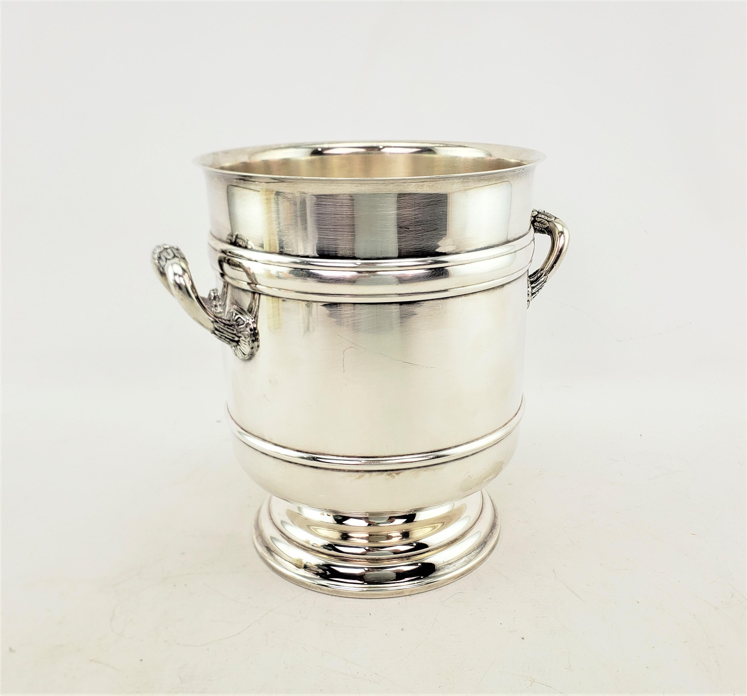 This vintage ice bucket or bottle chiller was made by the renowned Christofle company of France in approximately 1965 in an Art Deco style. This handled bucket is composed of silver plate with raised banding and a stepped pedestal base. The bottom