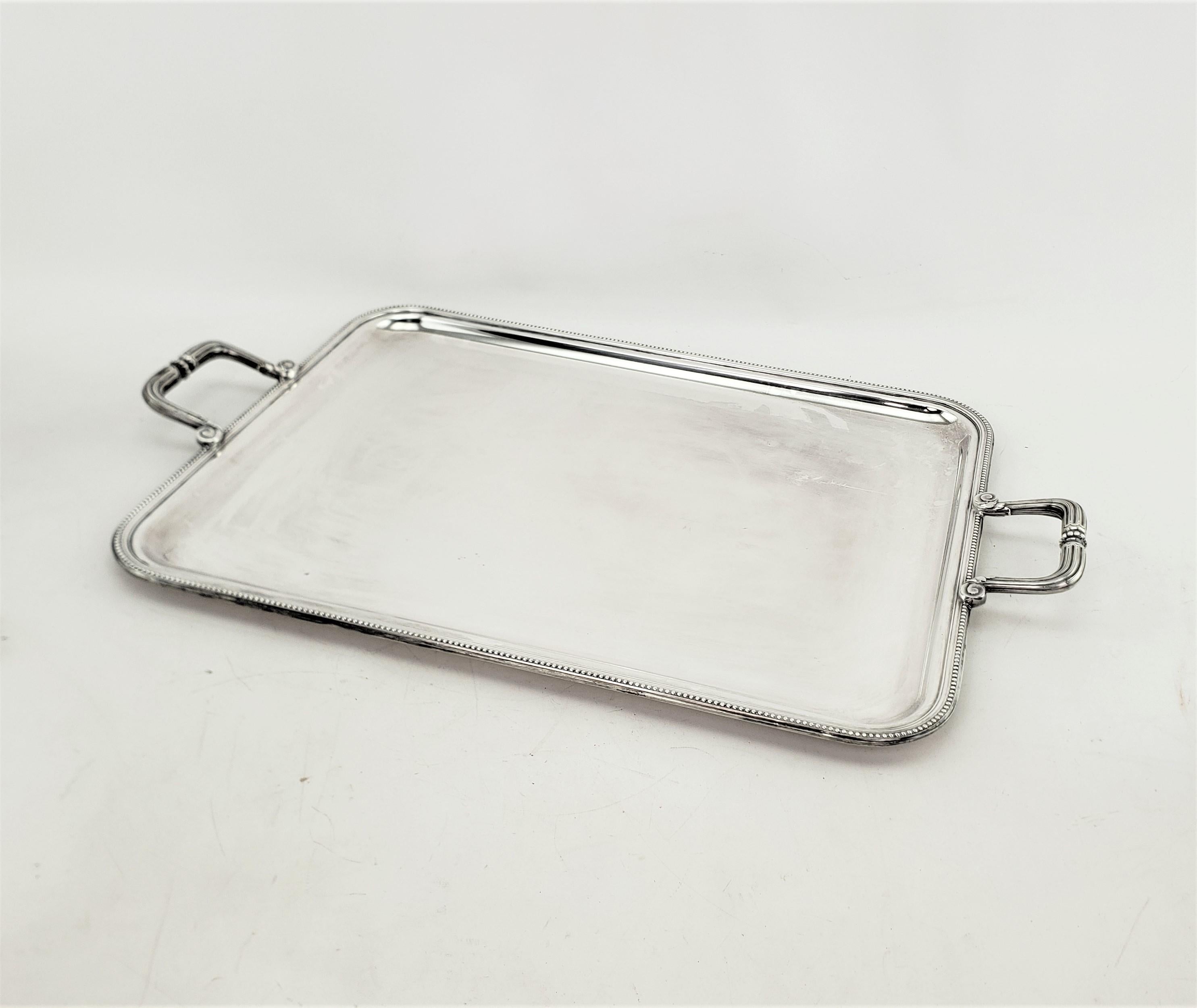 This vintage  serving tray was made by the renowned Christofle company of France in approximately 1965 in a period Mid Century style. The tray is composed of silver plate and has a smooth top surface with accenting stylized rope borders and matching