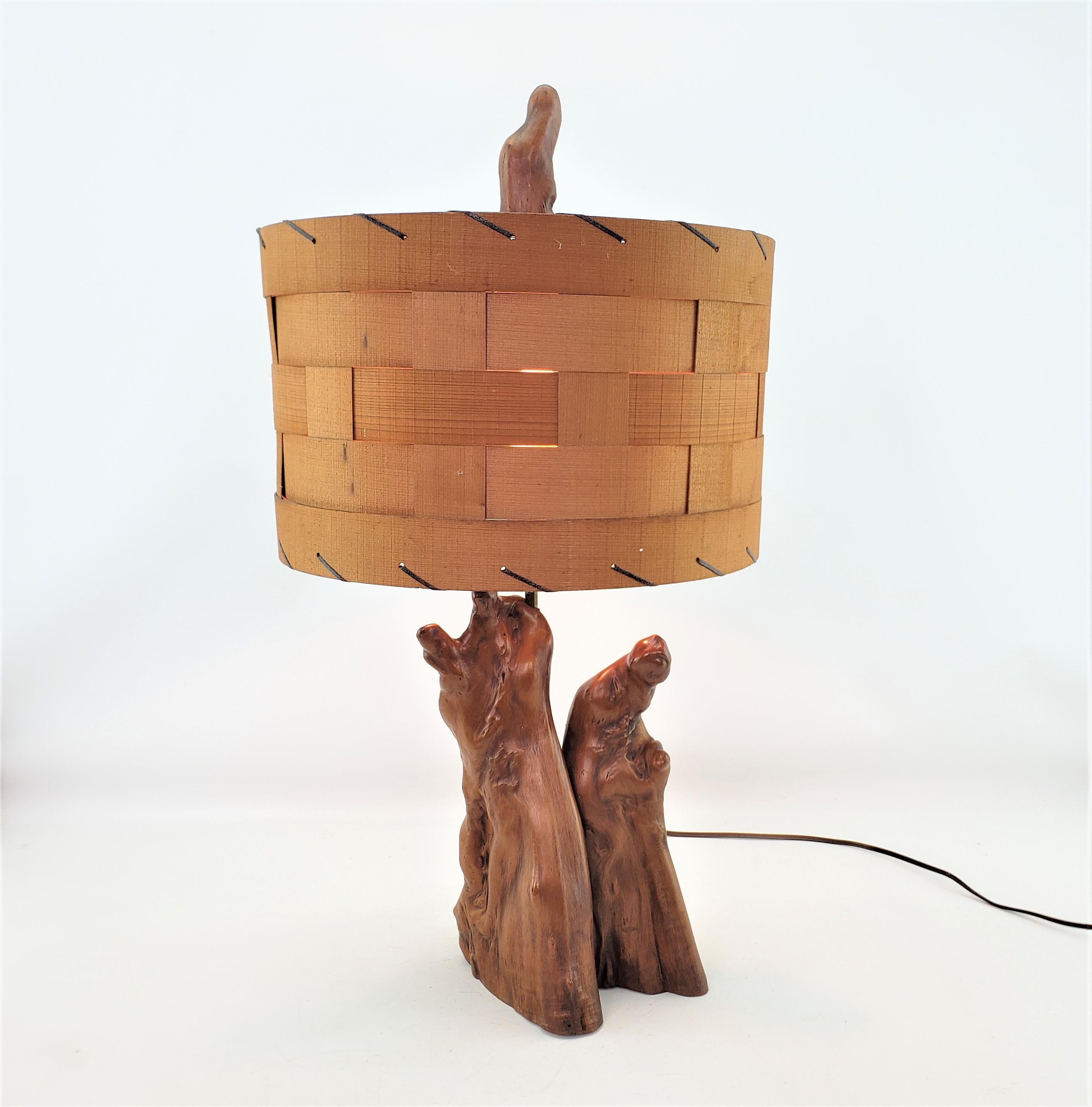 This vintage 'live edge' folk art table lamp was made by the Cypress Knee of New Ordleans, Louisiana of the United States in approximately 1960 in the period Mid-Century Modern style. The base of the lamp is composed of cypress wood knees which are