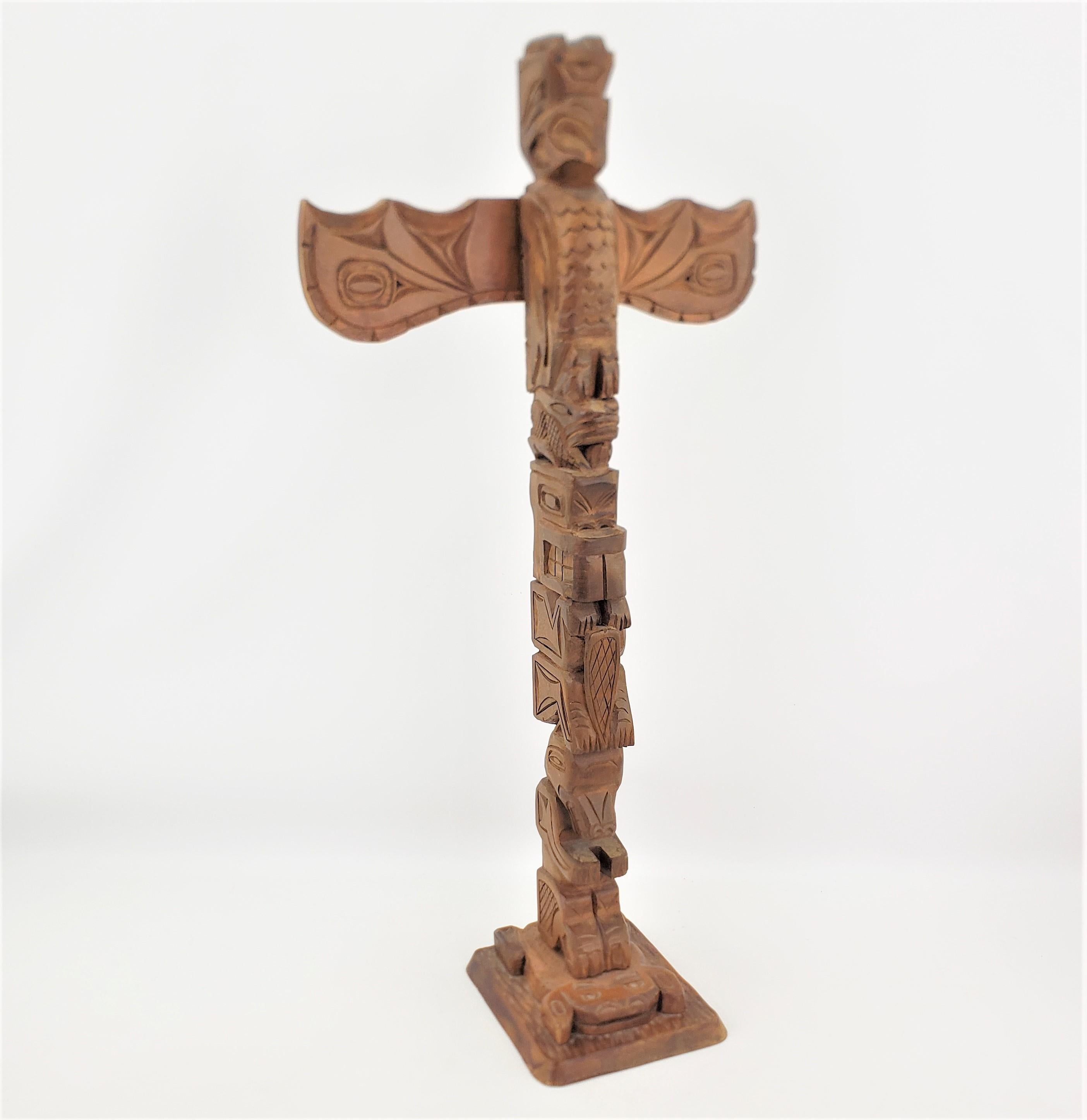 This hand-carved cedar totem is signed by an unknown artist and presumed to have originated from Canada and dating to approximately 1960 and done in the West Coast Indigenous Haida style. The totem is done in solid cedar and depicts several stylized