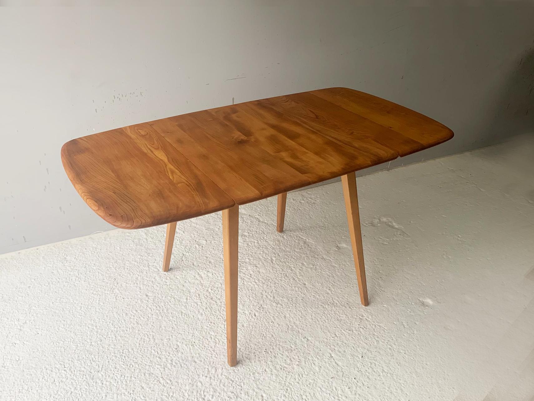 Vintage Ercol 492 dining table. Stylish design in solid elm and beech. Blue label dating back to the 1960’s. Beautiful vintage square dining table with spayed legs. Metal supports with wooden blocks at the end pull out from beneath the middle of the