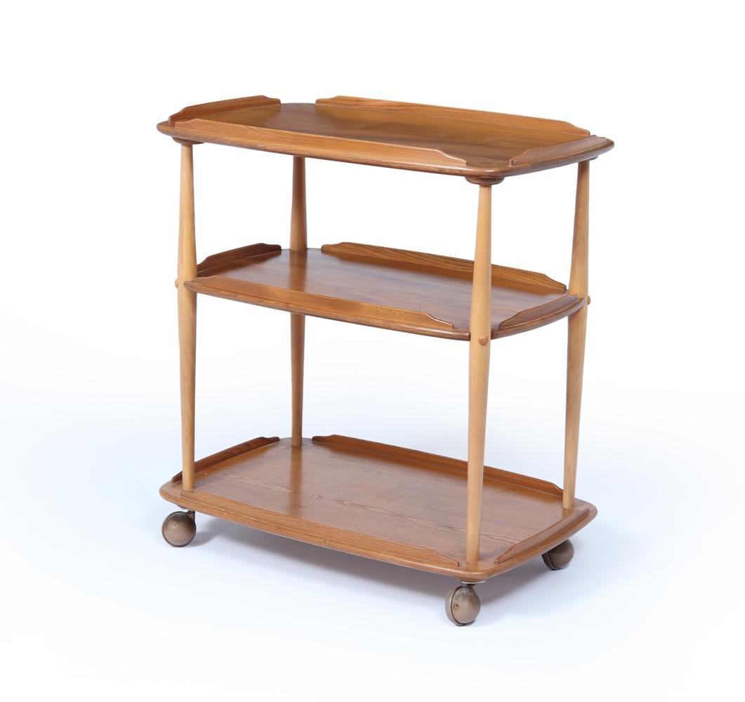 Chariot Ercol 
Un chariot Ercol intemporel du milieu du siècle, fabriqué en orme clair magnifiquement grainé avec un ton doucement mielleux qui reflète le célèbre savoir-faire de la marque. La structure à trois niveaux présente des plateaux aux