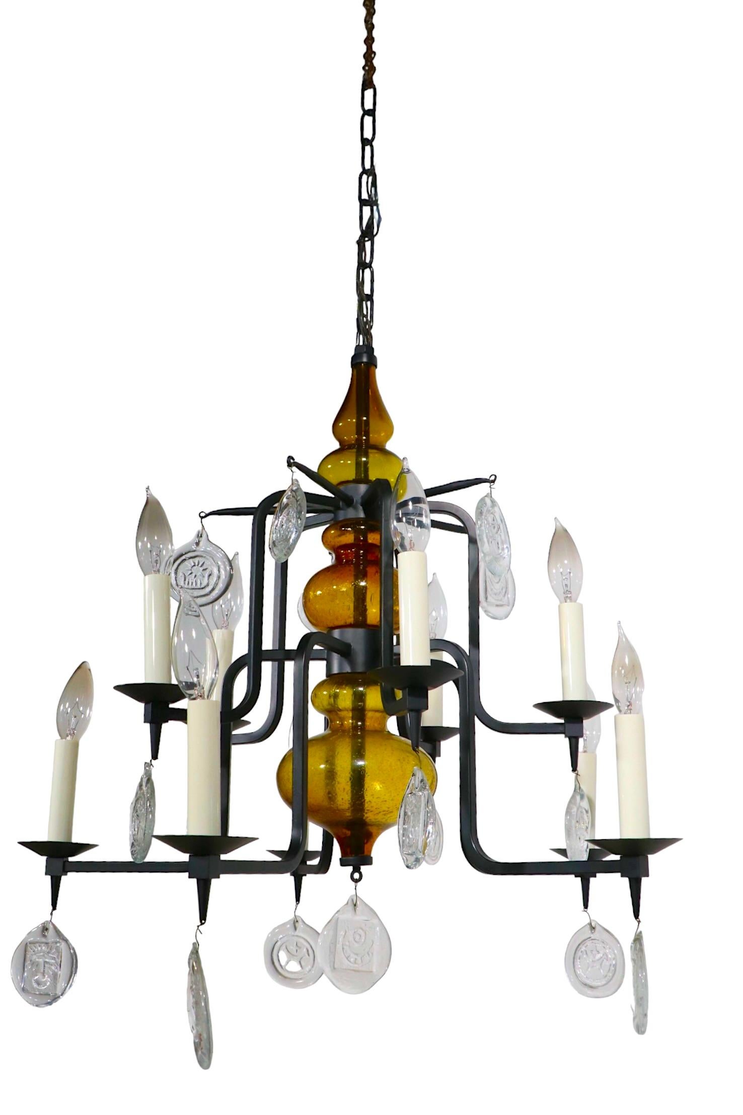 Exceptional Danish Mid Century Modern chandelier by Erik Hoglund for Body Nova, Made in Denmark circa 1950's. The fixture features two tiers each having 5 electrified  candle sconce arms, a wrought iron frame, with a  blown amber glass body, and the