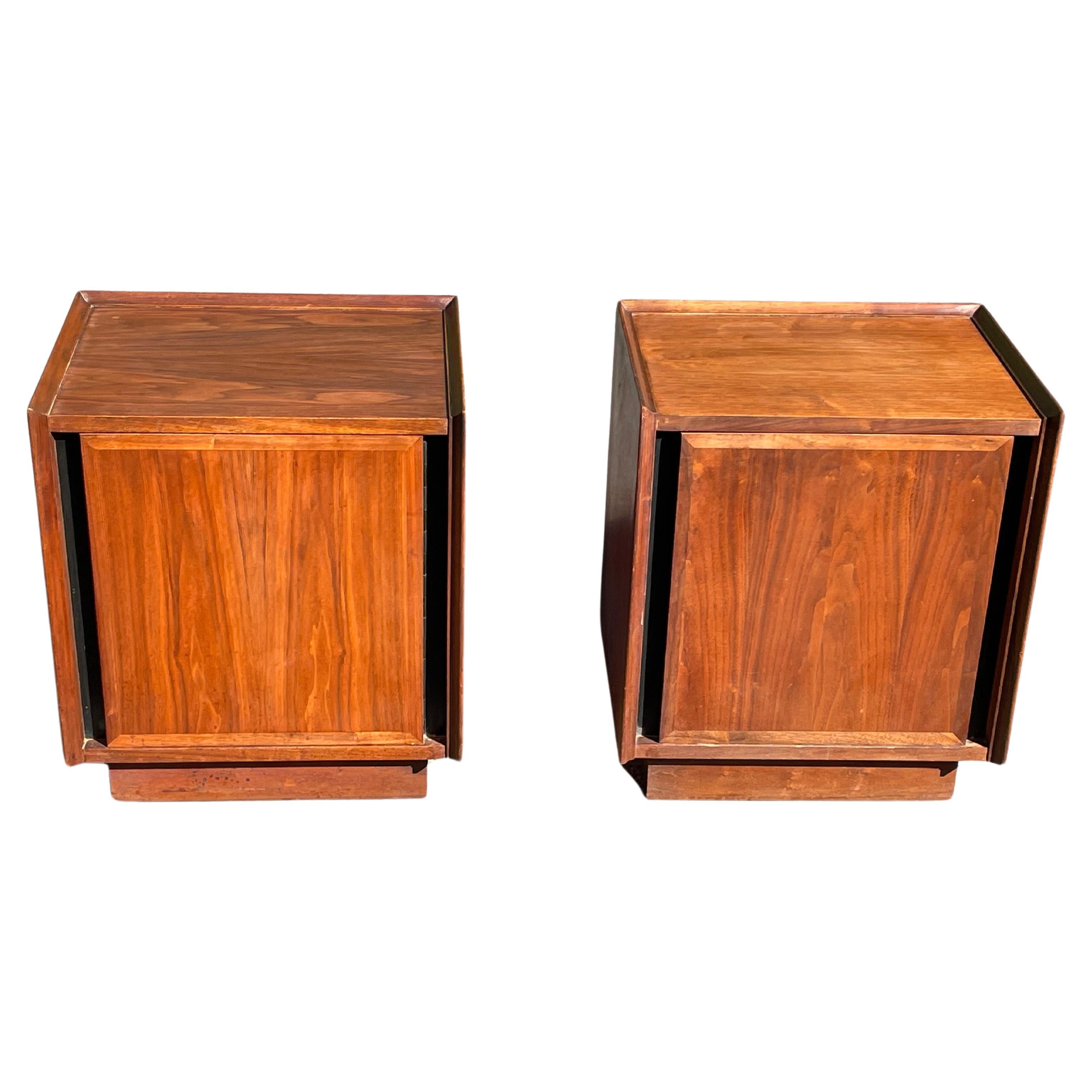 Pair of walnut nightstands by Merton Gershun for Dillingham, c.1960s, USA. The nightstands each feature a single door front with beveled sides. The hinged doors open to reveal a wide storage cabinet with pull-out white laminated drawers. The entire