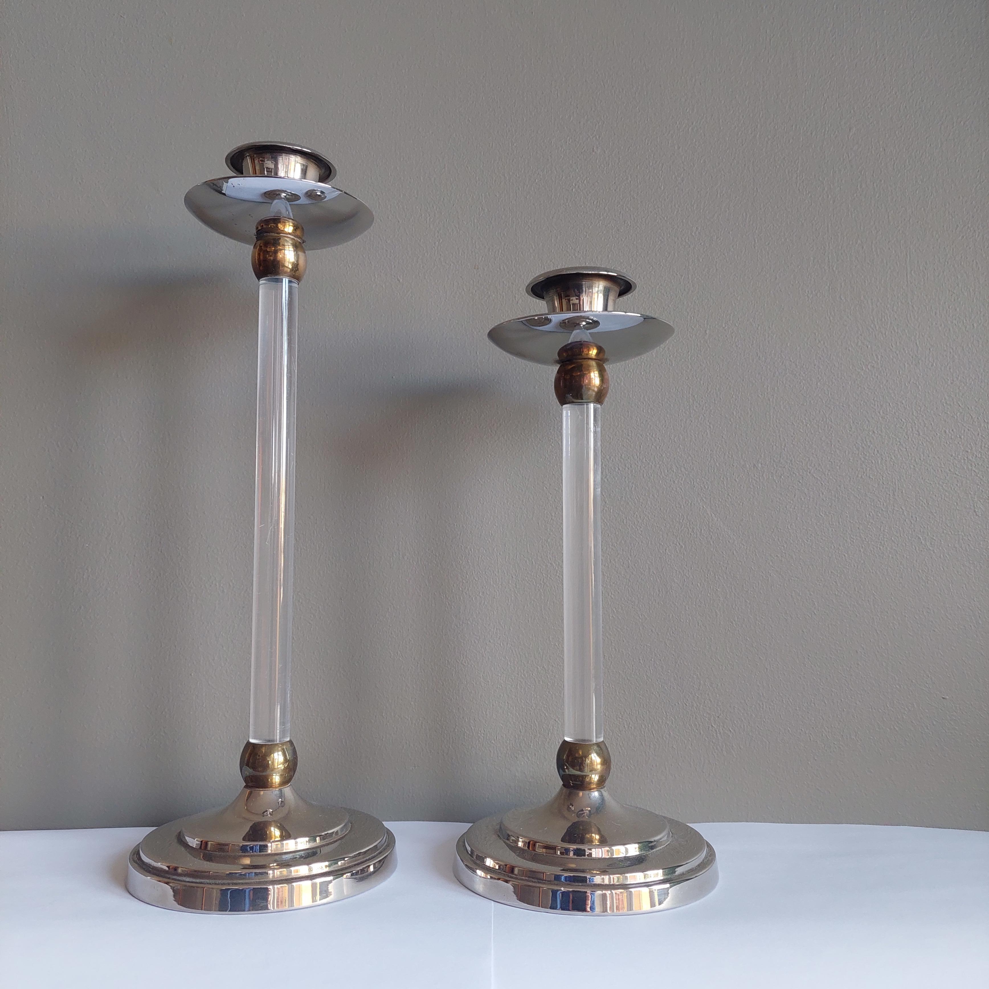 Estrid Ericson, paire de chandeliers en laiton doré et argenté. 
Base circulaire moulée en vernis argenté et surmontée d'une tige cylindrique en plexiglas ornée de deux anneaux en laiton à chaque extrémité. 
Les deux chandeliers se terminent par