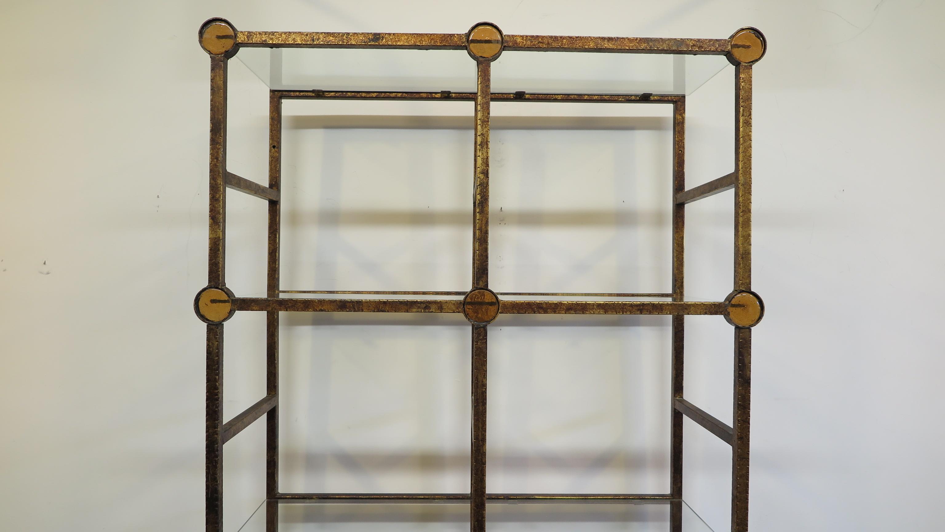 Italian midcentury etagere. Steel with gilt antique finish frame detailed with circular artisan amber toned glass roundels having six glass shelves. A Mid-Century Modern etagere. Very good condition.