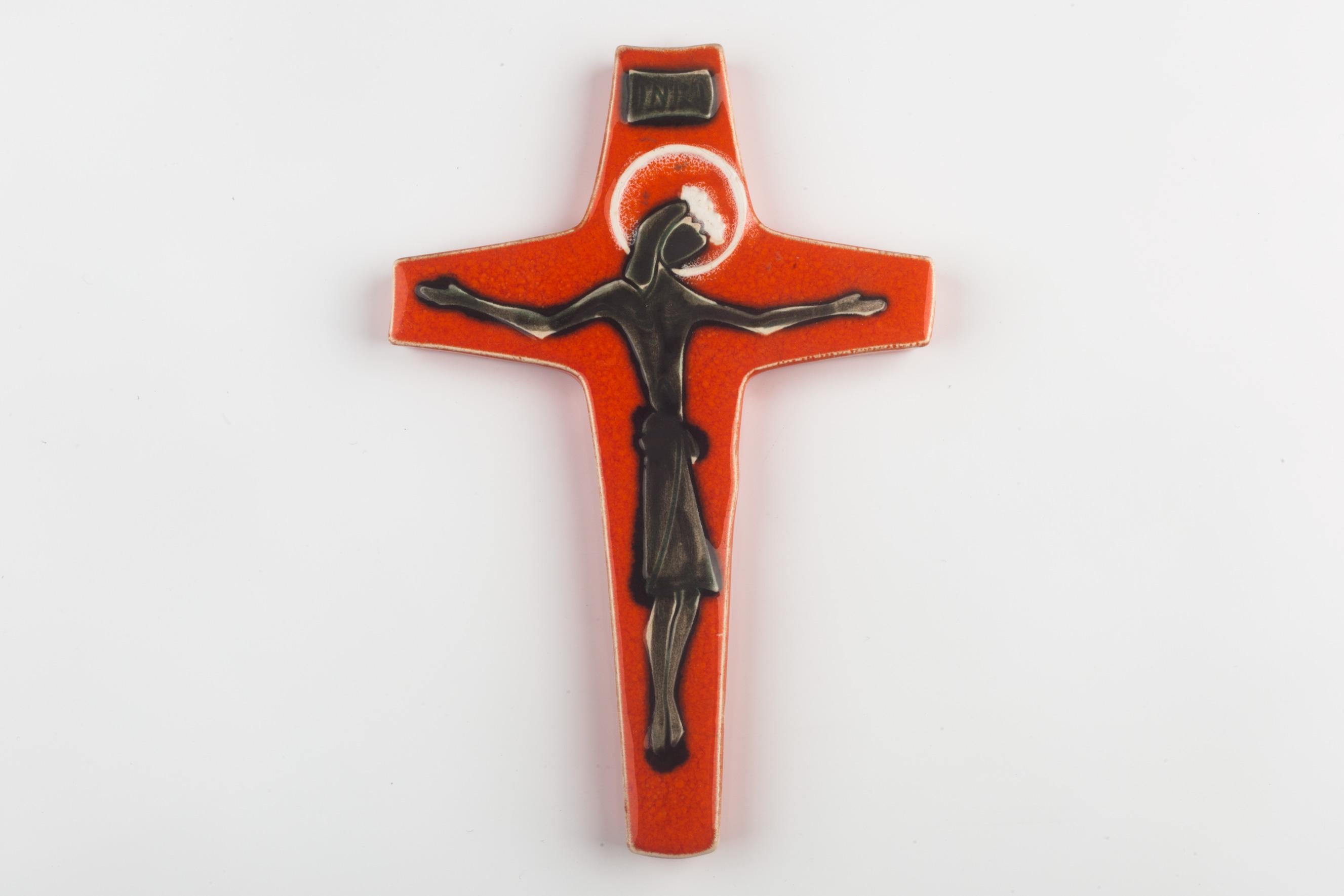 EEuropean mid-century crucifix in glazed ceramic, hand-painted in bright orange and green with gracefully floating Christ figure at its center in subtle volumes. A one-of-a-kind, handcrafted piece that is part of a large collection of crosses made