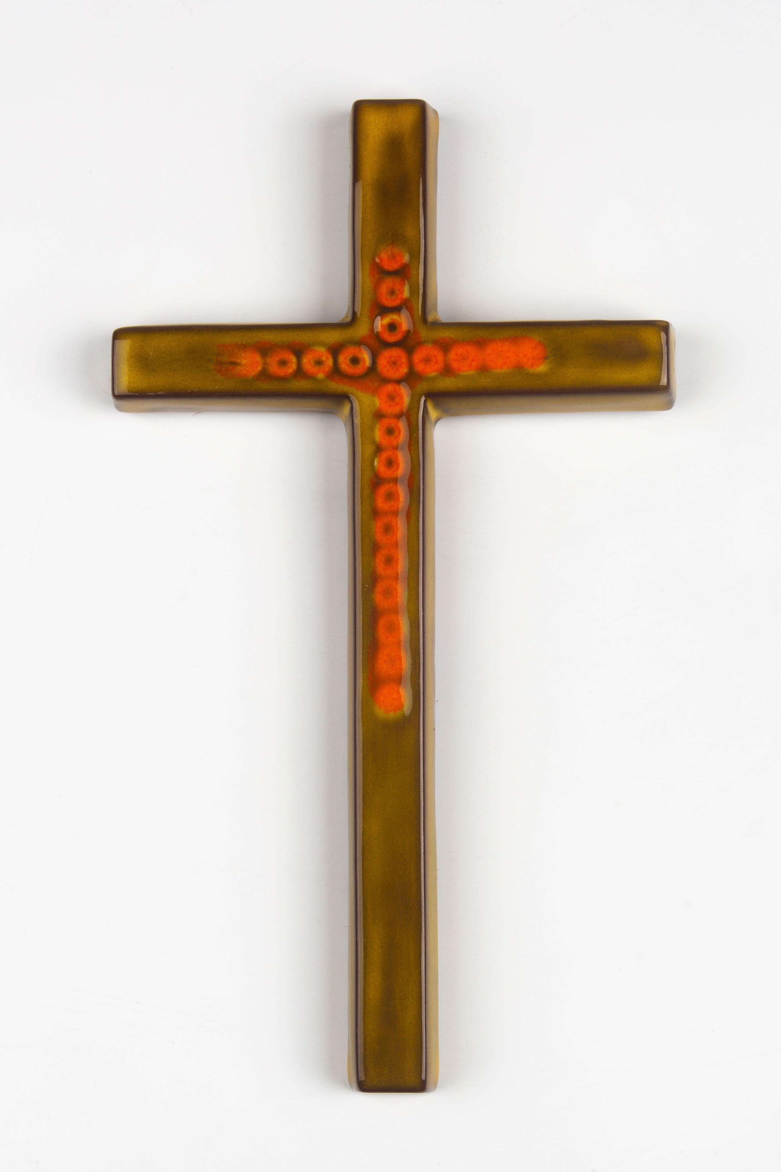 Midcentury European ceramic wall crucifix in green and orange from a large collection of crosses handmade by Flemish artisans. High gloss glaze over olive green cross with decorative orange hand painted design. 

From modernism to brutalism, the