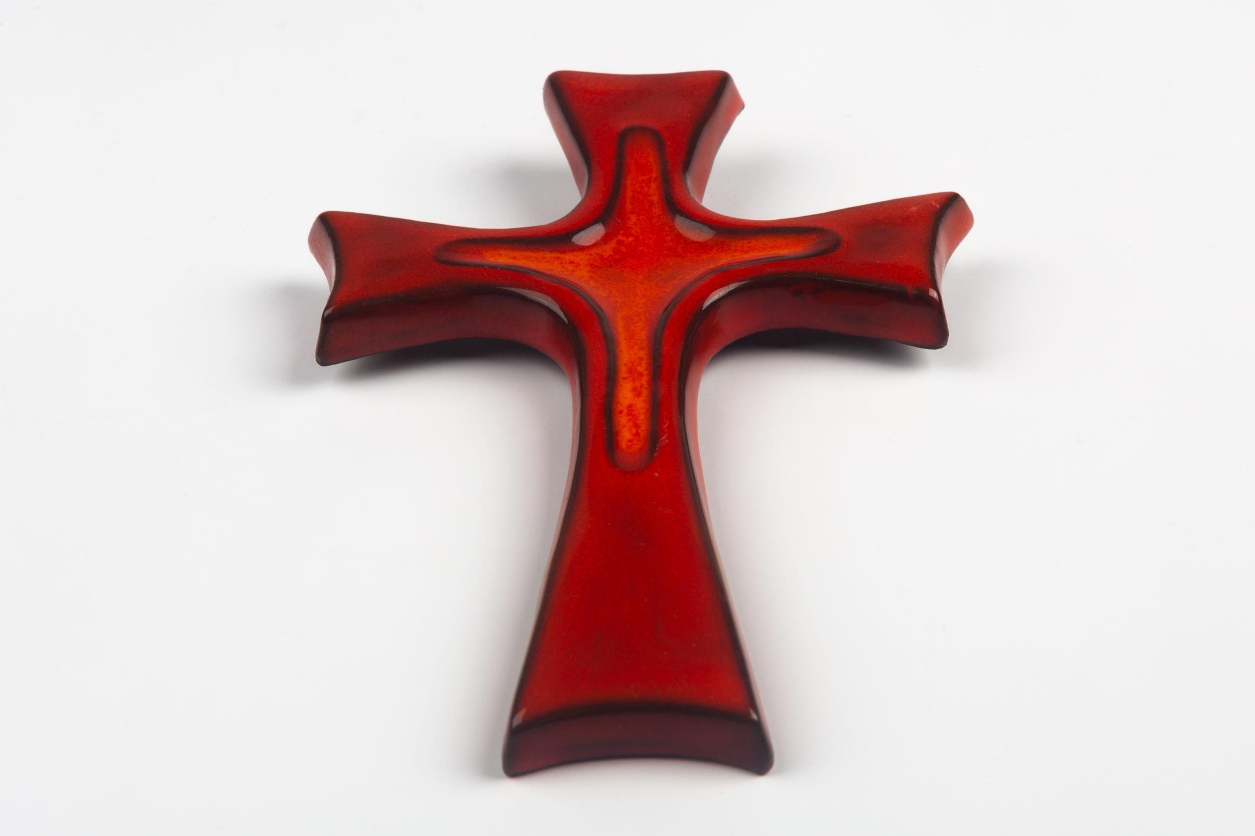Midcentury European ceramic wall cross in red with dark brown, almost black decorative outlining and high-gloss glaze. From a large collection of crosses handmade by Flemish artisans. 

From modernism to brutalism, the crosses in our collection