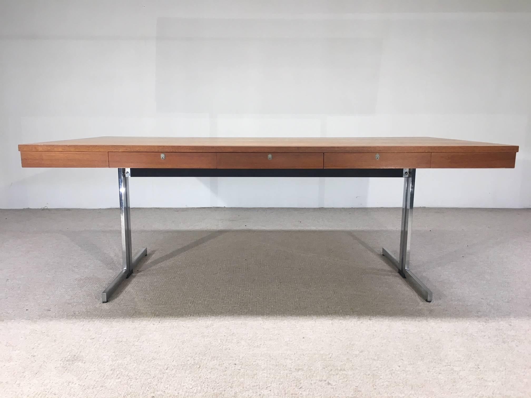 Teak executive desk having splayed chromed steel base attributed to Walter Knoll and produced by Pfandsiegel-Germany, circa 1960.
Keys not present. Wonderful, well maintained vintage condition.
Measures: H 30.75 in. x W 78.75 in. x D 39.5