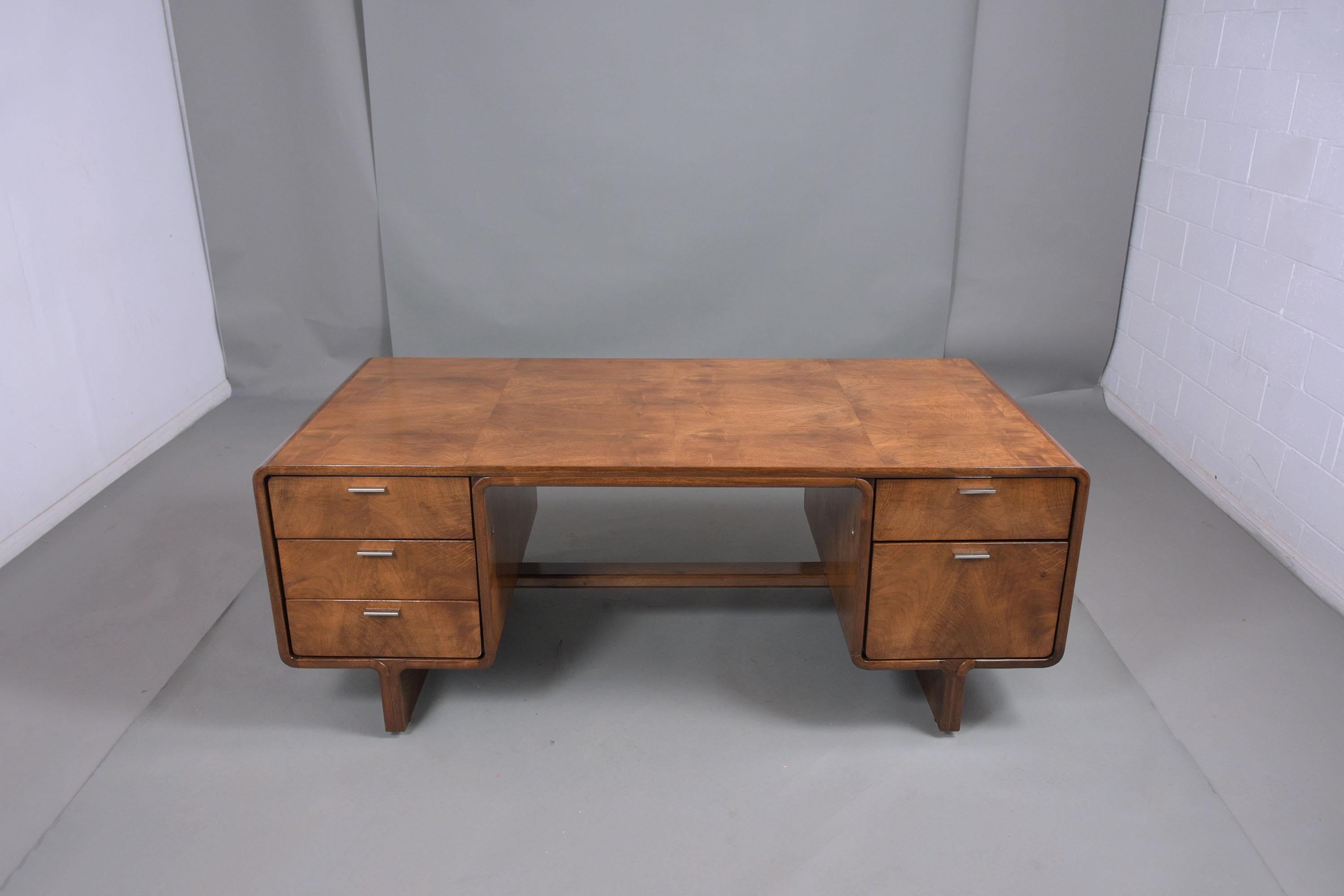 An extraordinary Mid-Century Modern desk hand-crated out of walnut wood newly stained a rich walnut color with a lacquered finish and professionally restored by our team of craftsmen. The desk features a large rectangular top with curved edges is