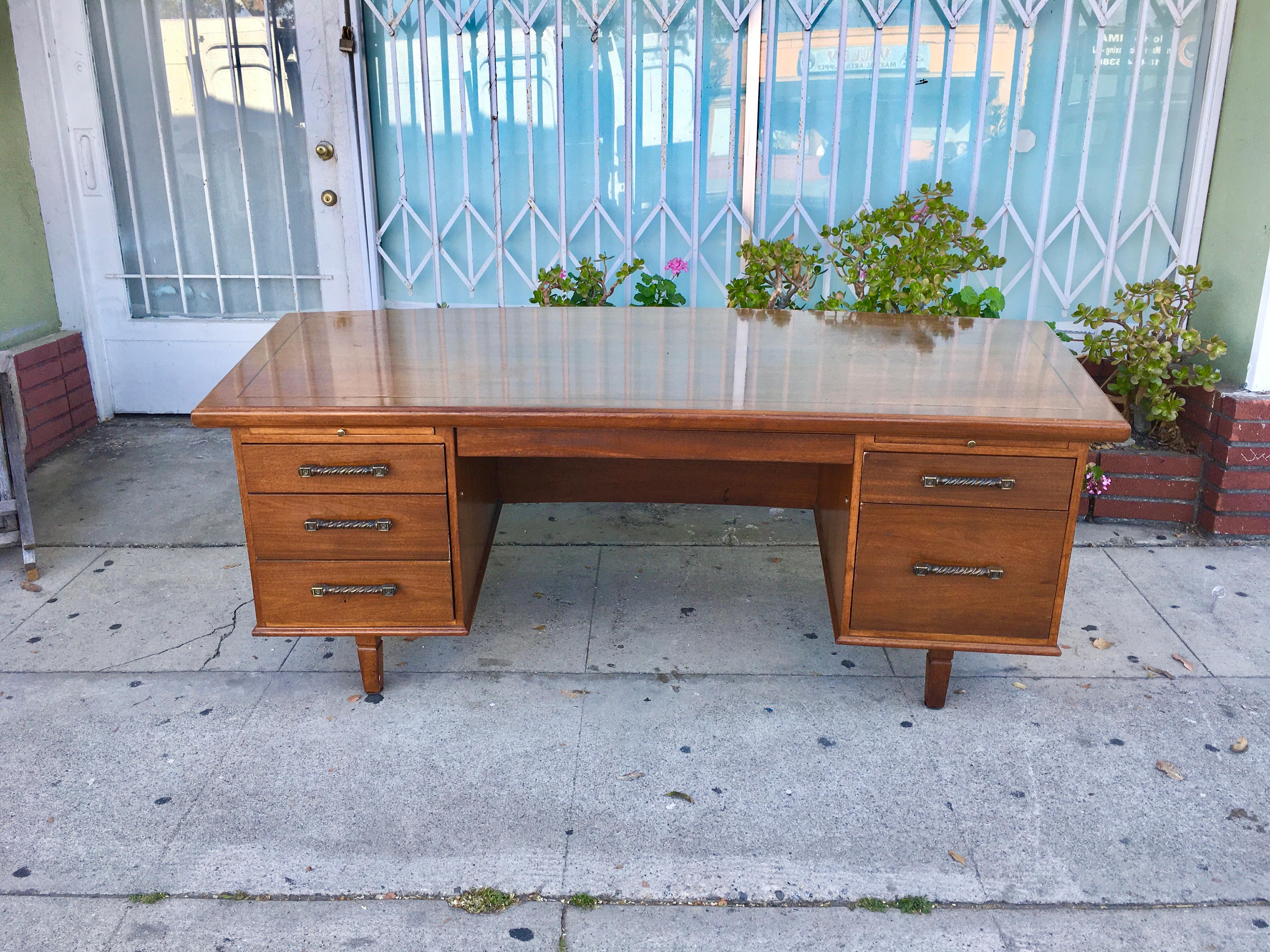 Beautiful executive walnut desk by Monteverdi young. This executive desk features an excellent walnut finish with four drawers and a file drawer. Each has an aesthetically constructed handle, giving it that perfect mid-century style.
