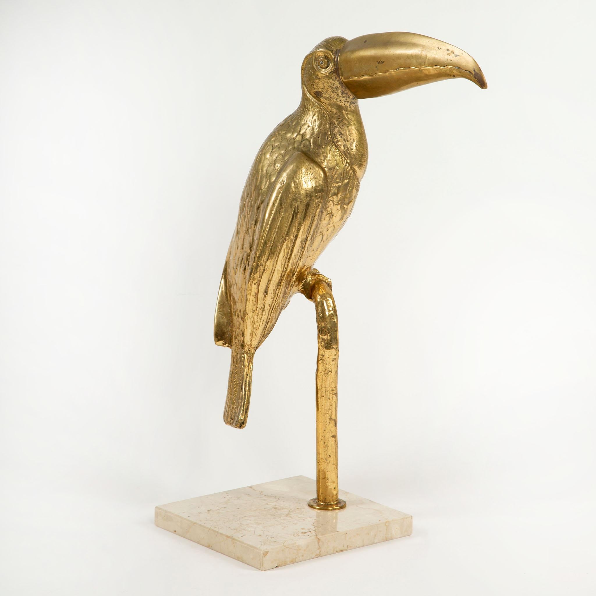 Un'impressionante scultura decorativa raffigurante un tucano, finemente fusa in ottone e montata su una solida base di marmo. Il pezzo cattura la silhouette distintiva dell'uccello esotico con il suo becco curvo e sovradimensionato, il corpo