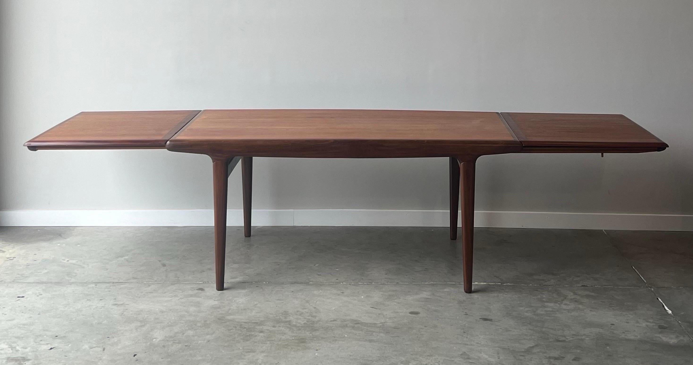 Danish expanding dining table designed by Johannes Andersen for Uldum Møbelfabrik, circa 1960s. Made from teak wood with a vibrant grain pattern. Rectangular in shape with rounded corners. The center of the table is surrounded by a darker border