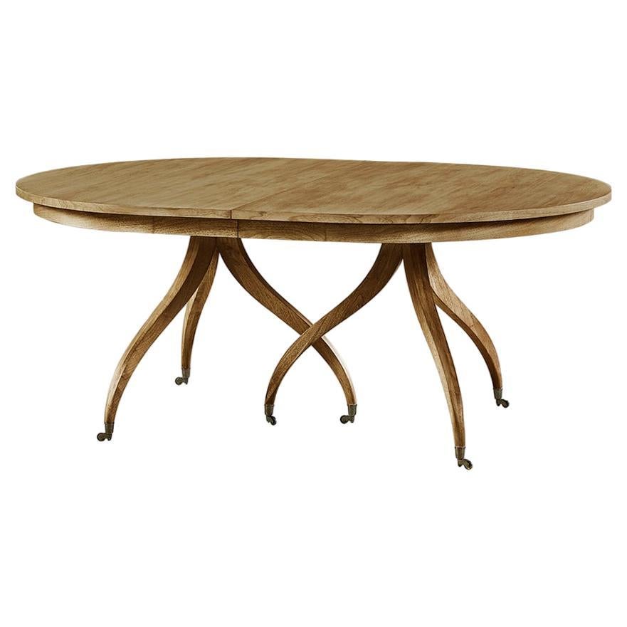 Inspired by an early 19th-century Regency design, this dining table is timeless and features an elegant and functional design. The oval extending table is perched atop sinuous, flowing classic spider legs with brass castors. A warm sun-bleached