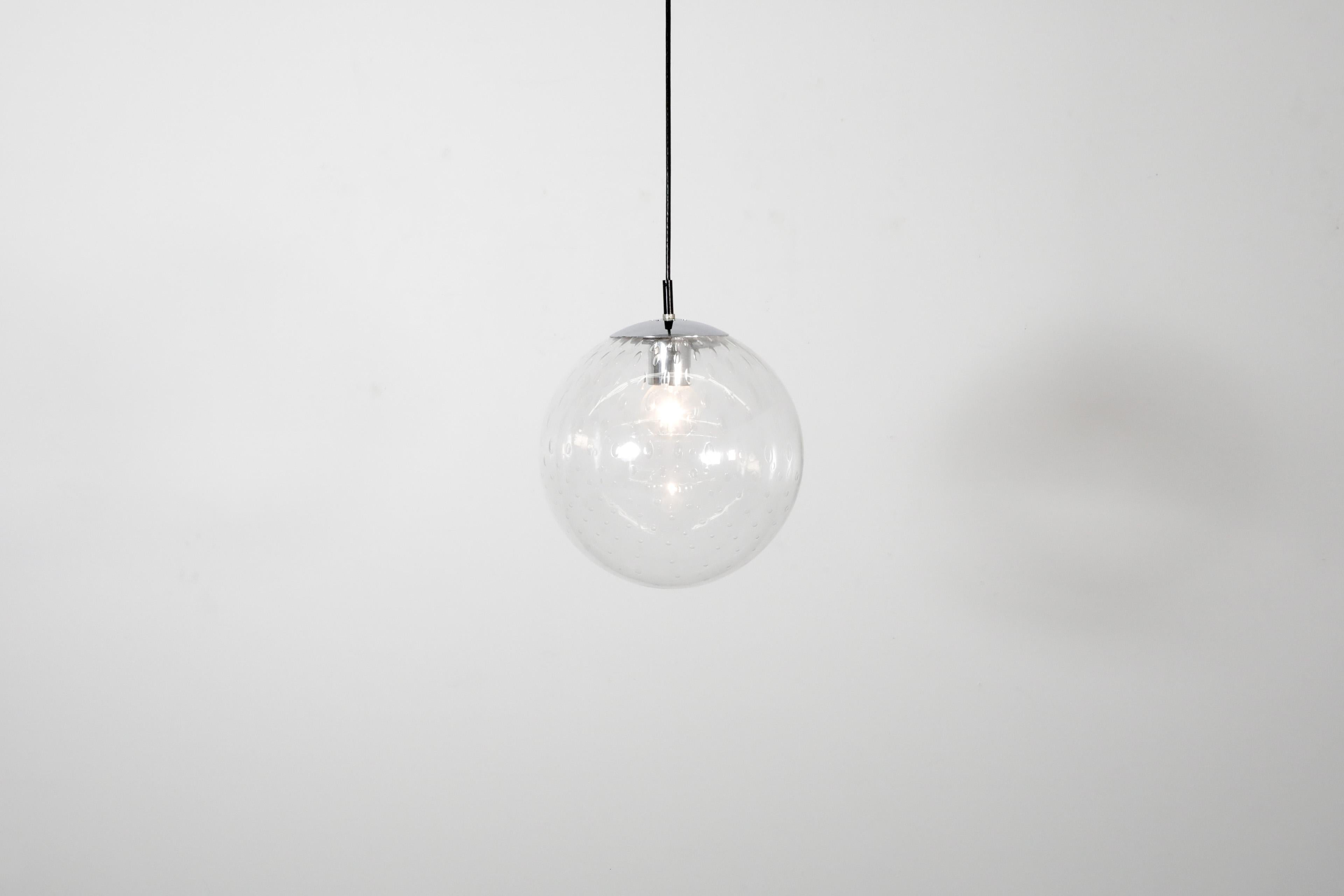 This large, mid-century blown glass globe ceiling light with chrome hardware was manufactured by the trail-blazing Dutch lighting manufacturer Raak.  It features decorative bubble design in glass and handsome chrome hardware. Simple, classic, clean