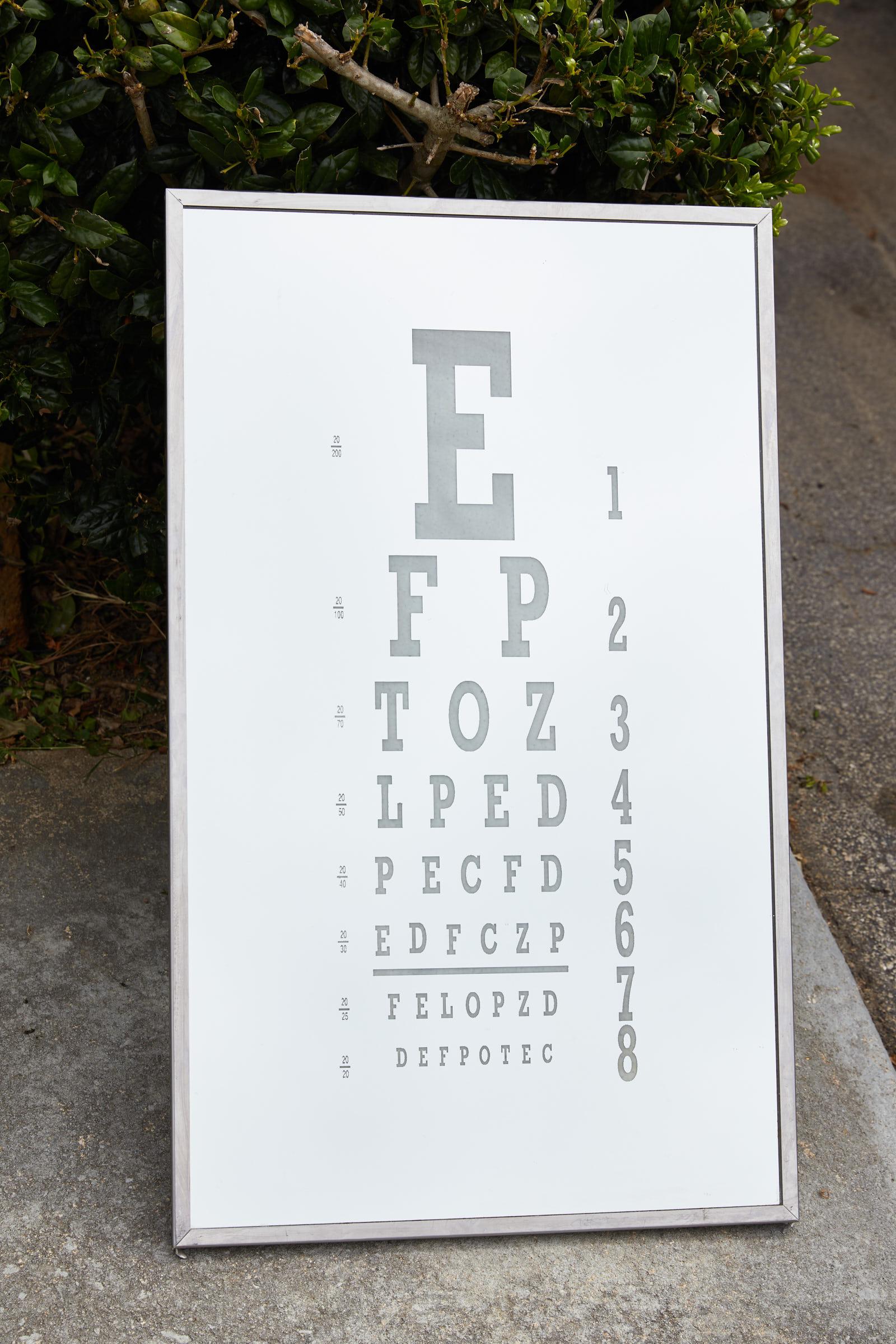 Vintage optometrist office mirror in a chrome frame and having an eye chart in relief, circa 1940s.