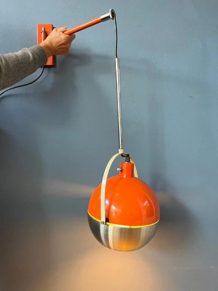 Very rare orange space age wall lamp with hanging eyeball shade. The shade can be turned in different directions. The height of the shade can also be adjusted. The lamp requires one E26/27 (standard) lightbulb and currently has an