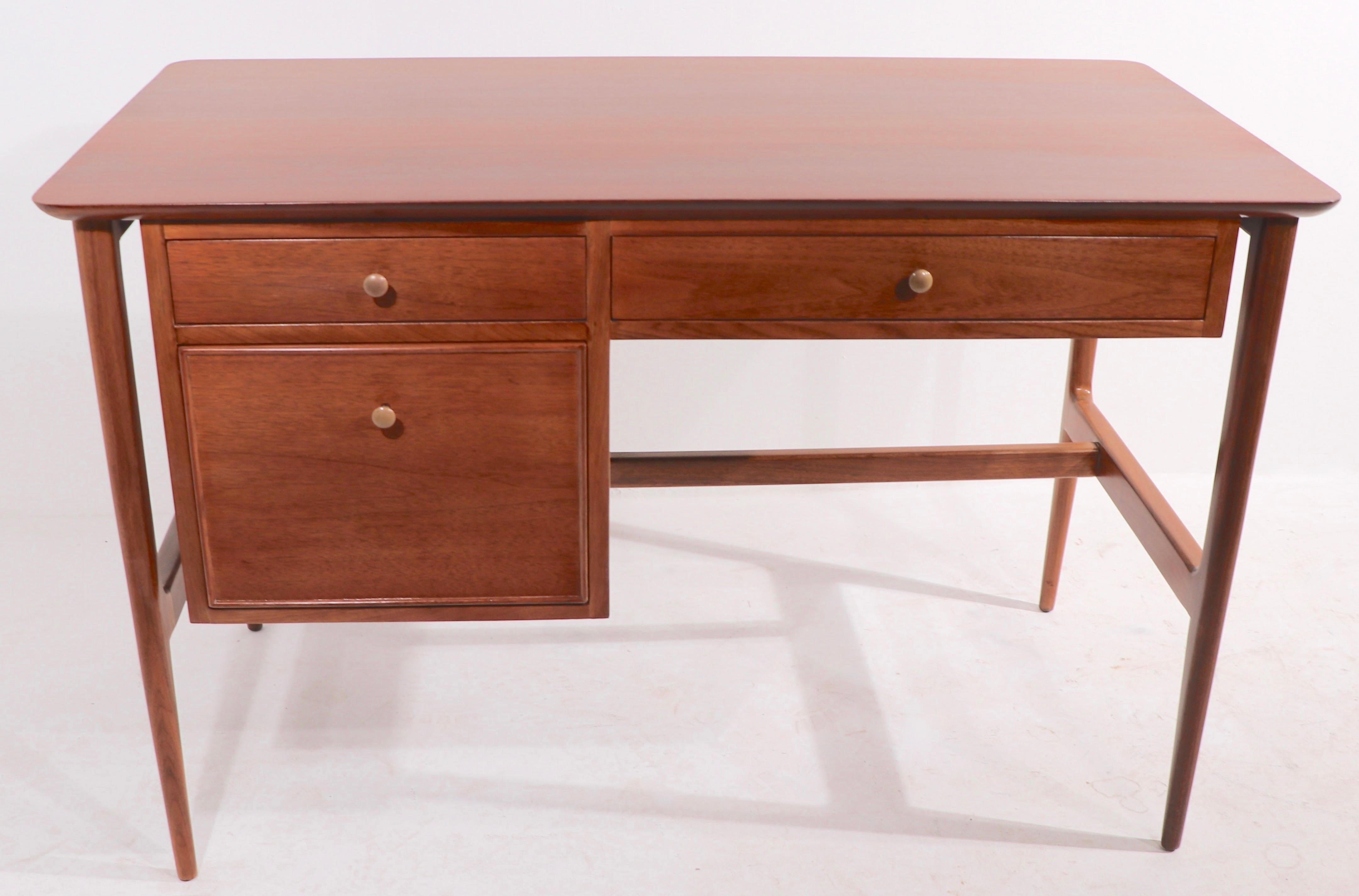 Stylish Mid Century desk from the Facade series by John Stuart. The desk features three drawers, it has an exposed sculptural frame which supports the drawers and top surface. This example has been newly professionally refinished, and is in
