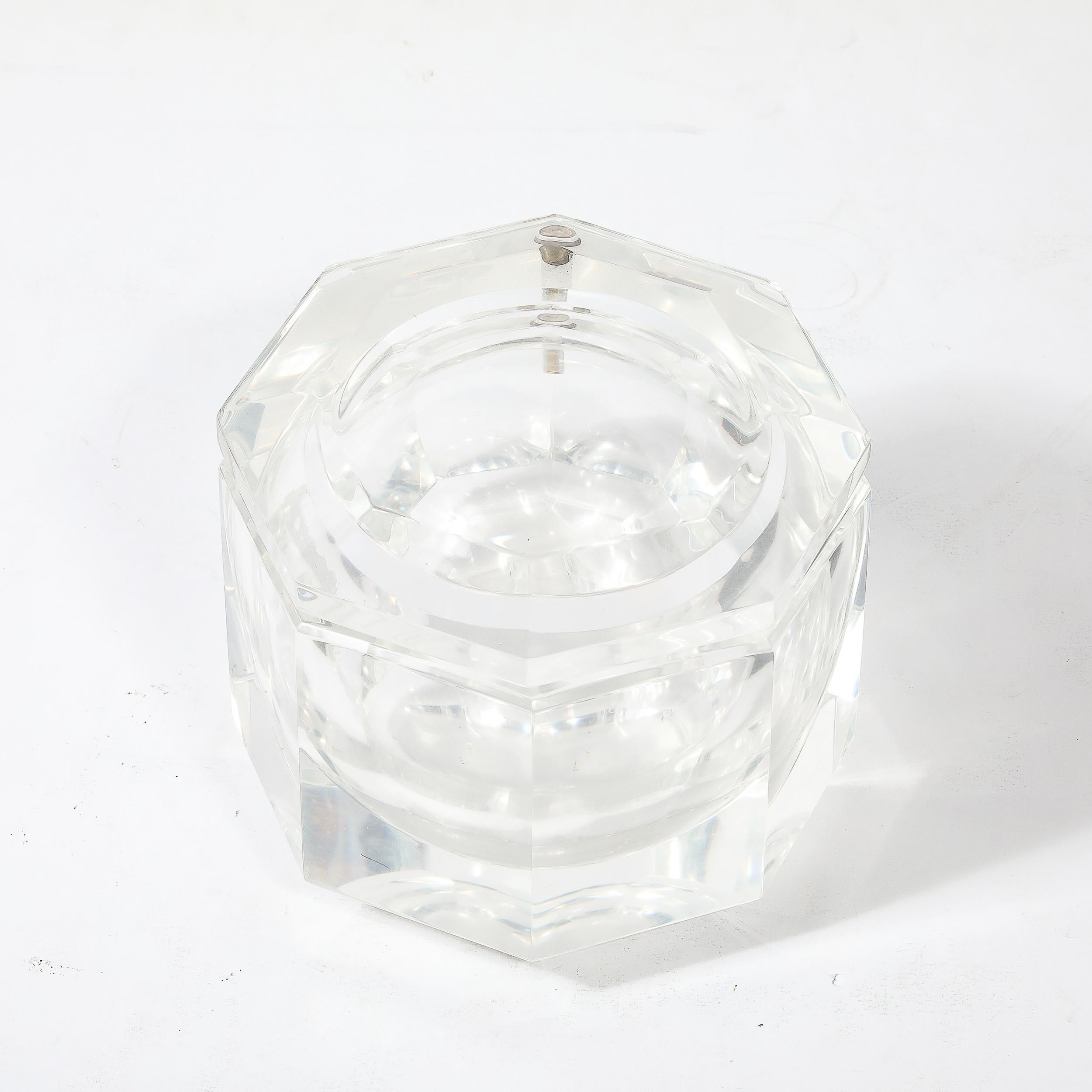 Esta elegante cubitera octogonal moderna de mediados de siglo fue realizada en Estados Unidos por la estimada diseñadora Carol Stupell, hacia 1970. Presenta un cuerpo facetado y una parte superior compuesta de Lucite translúcido facetado, lo que le