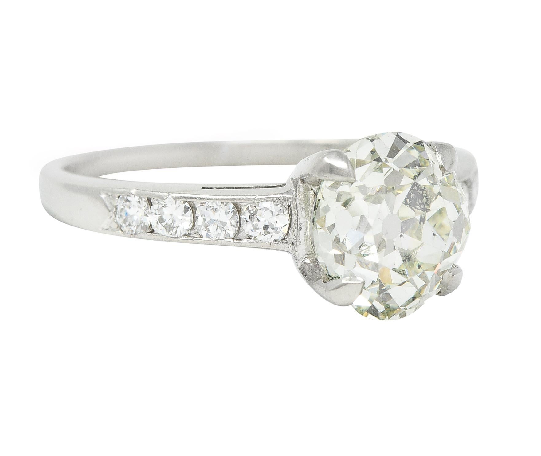 Centering an old mine-cut diamond weighing approximately 1.95 carats - fancy light greenish-yellow in color with SI2 clarity 
Prong set in basket and flanked by cathedral shoulders with channel set old European cut diamonds 
Weighing approximately