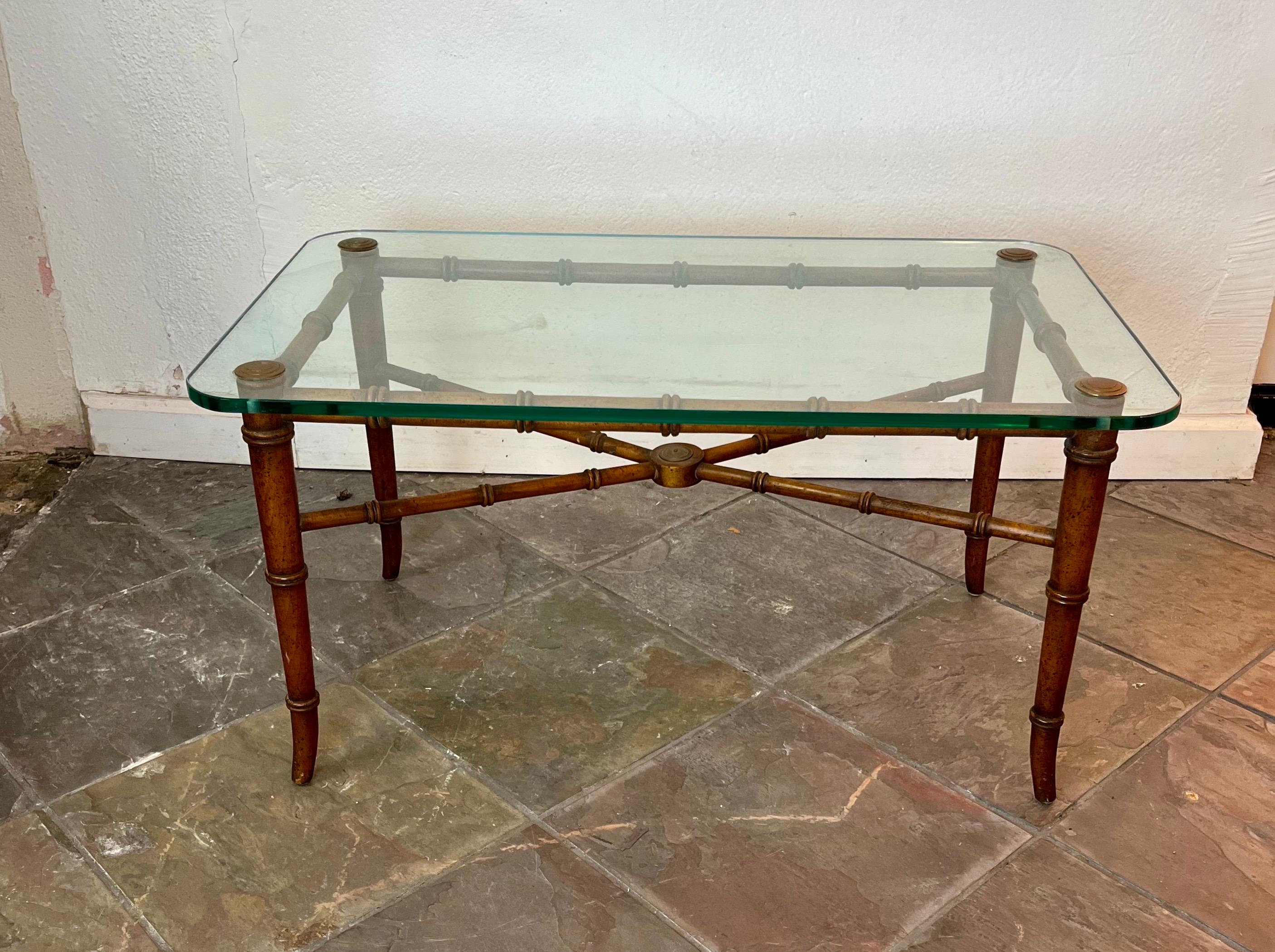Mesa de centro o de cóctel clásica de bambú sintético. Bonito diseño y escala. El armazón, con profundos detalles tallados, sostiene la tapa de cristal de bordes redondeados, sujeta con tapas de latón. 
De acera a NYC/Philly 450 dólares