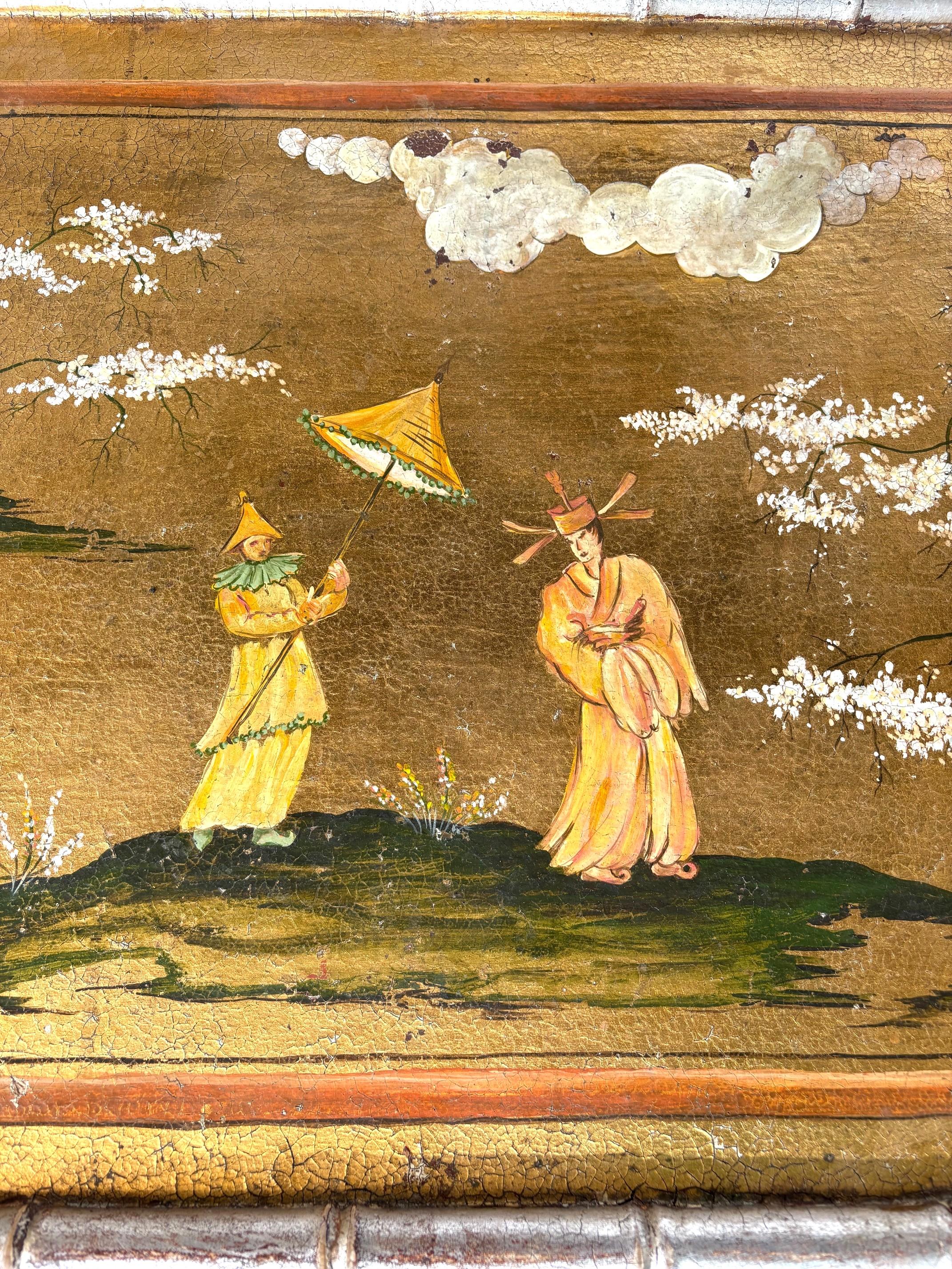 Un superbo tavolino da caffè Chinoiserie di design con una base in finto bambù. Decorato in stile orientale con scene dipinte a mano. Una patina invecchiata di oro e argento dorato. Il tavolo poggia su una base in finto bambù dorata in argento.